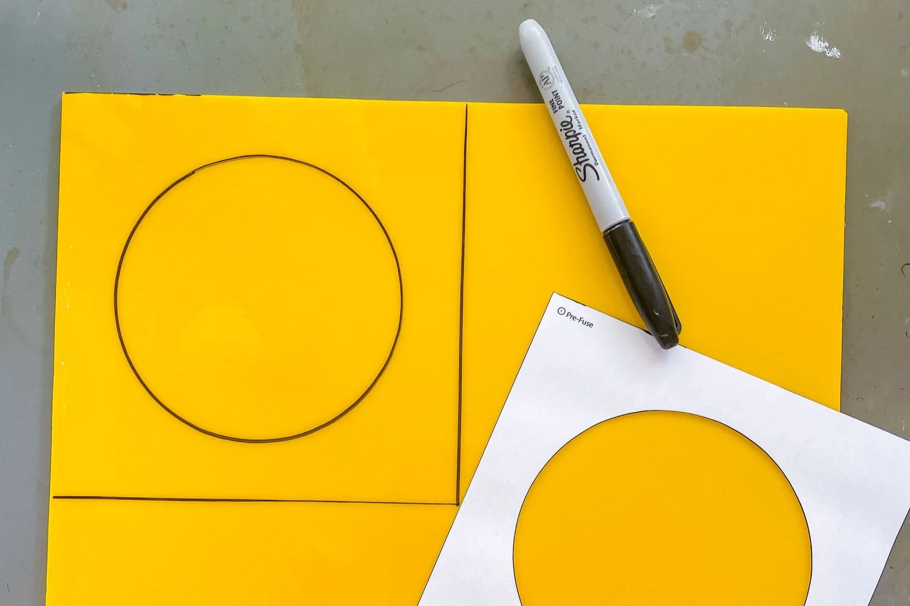 A yellow piece of stained glass with a circular cutout pattern drawn on its surface