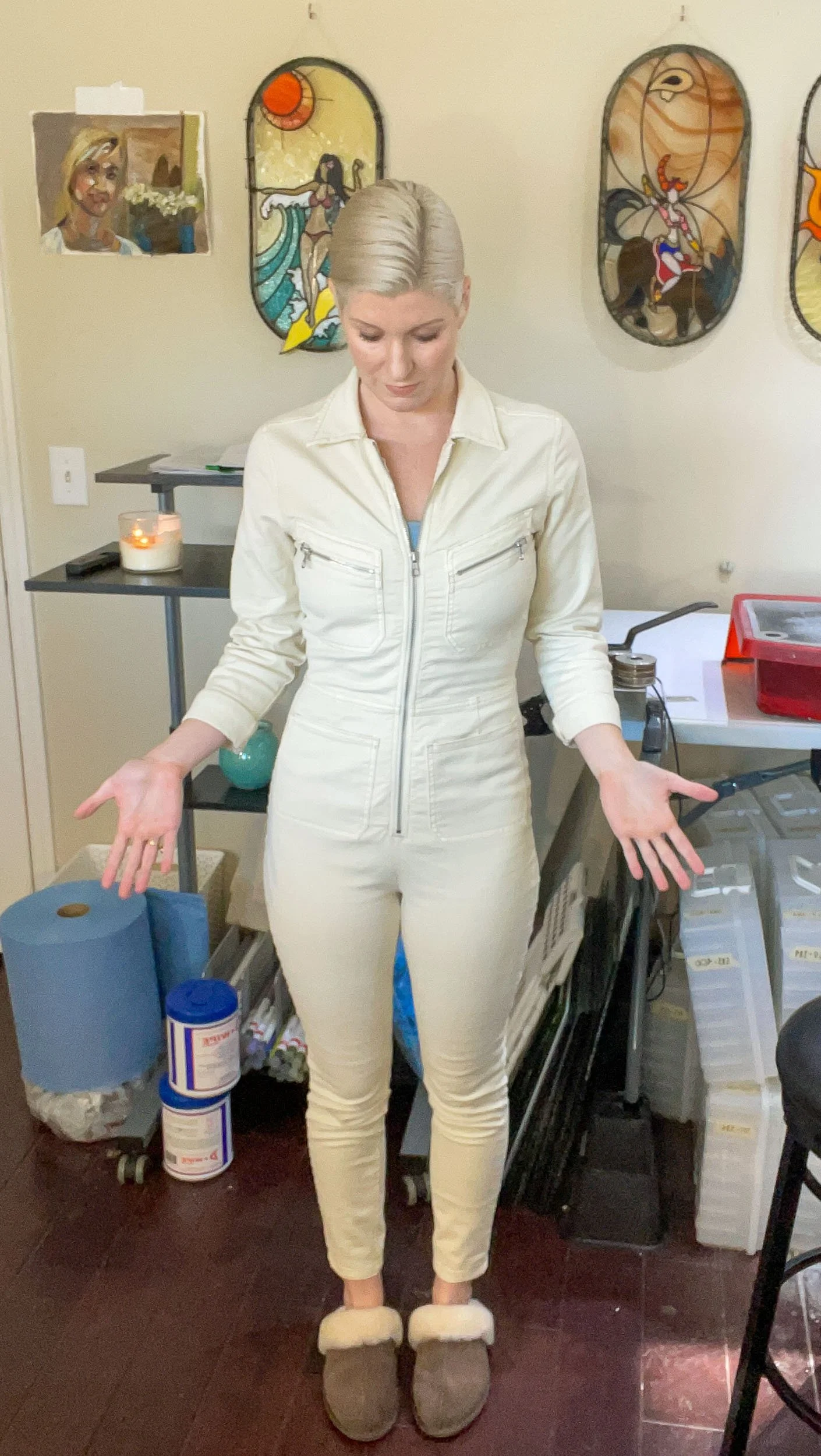 Woman wearing a long-sleeved, long-legged white jumpsuit in a stained glass studio