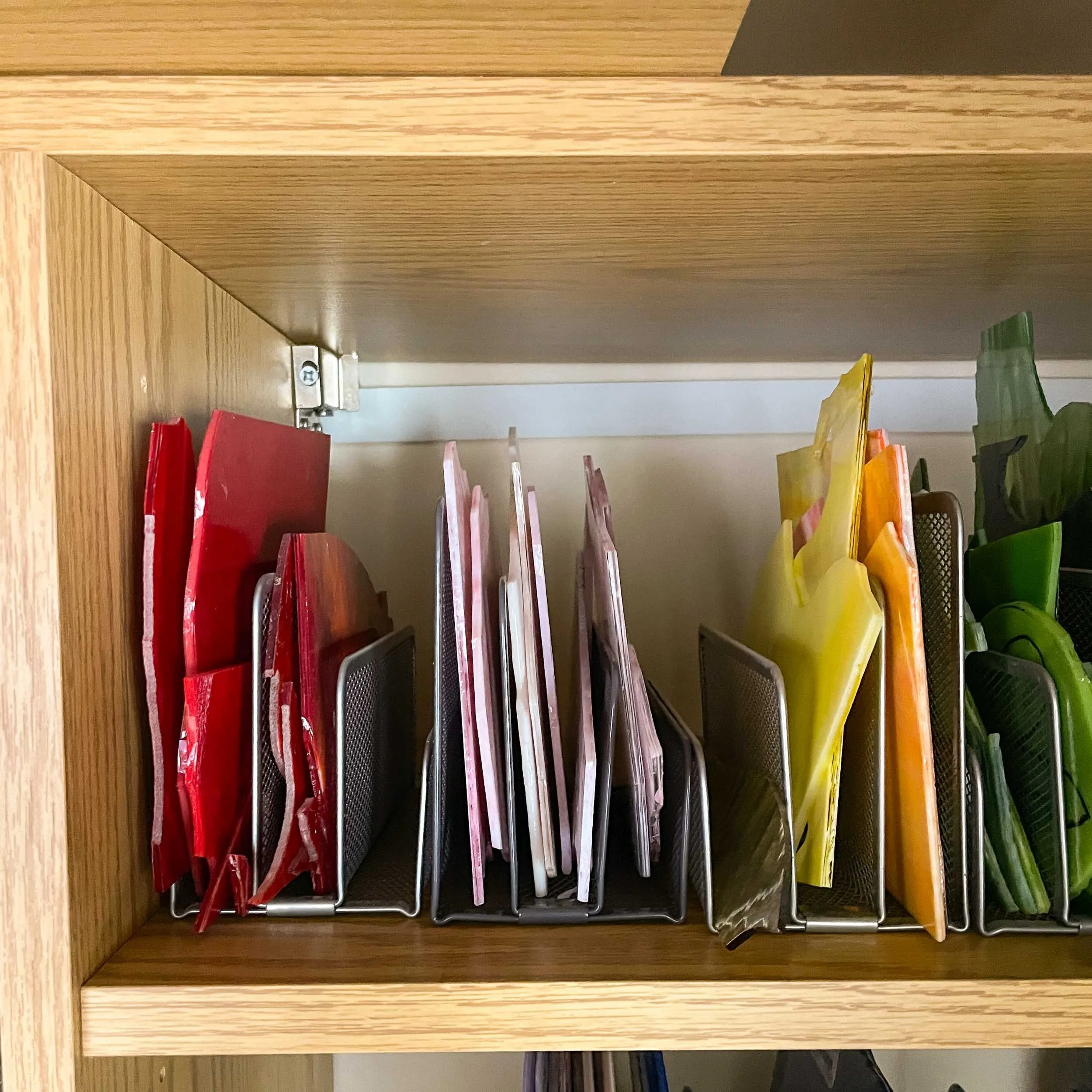 Several small stained glass sheets stored in a metal letter holder