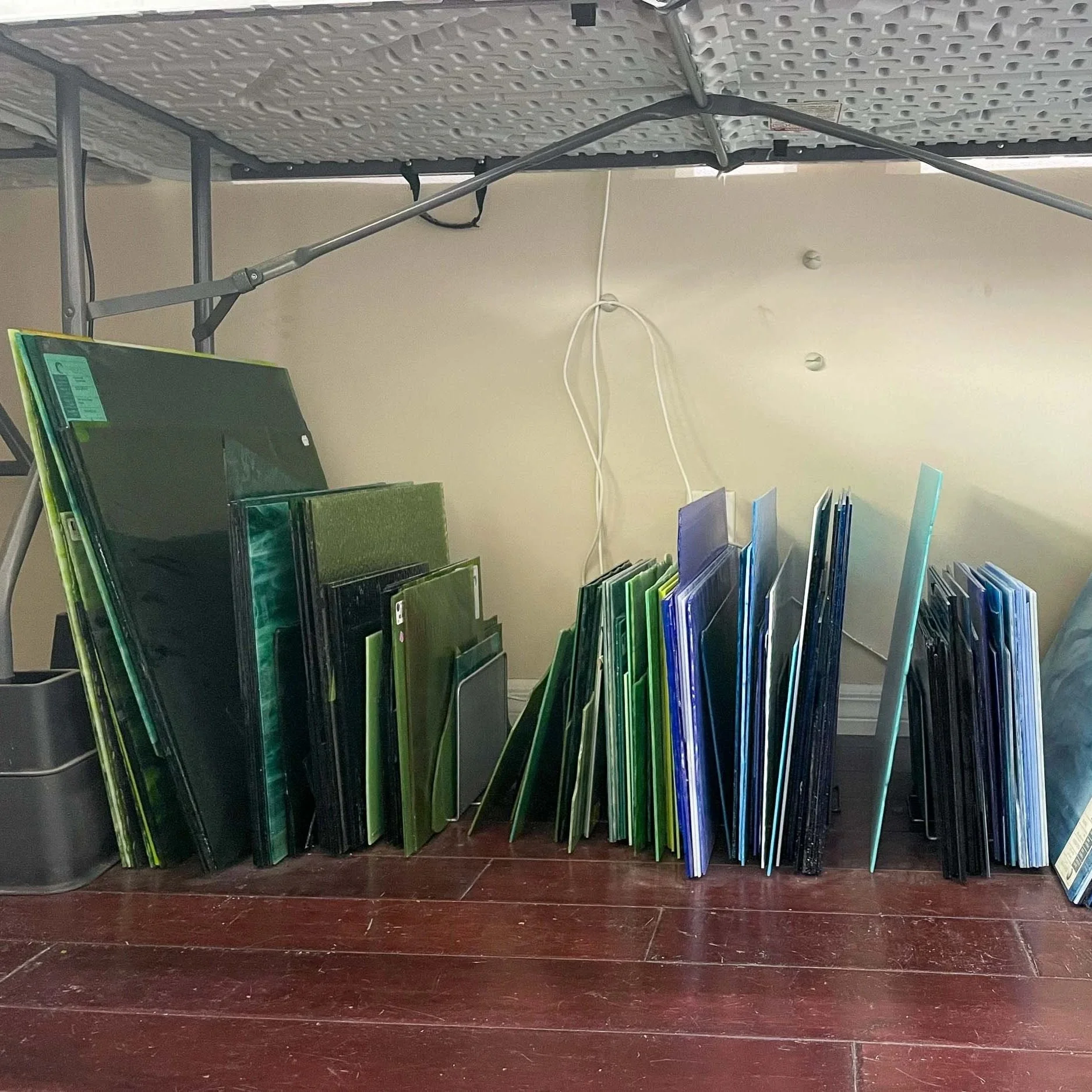 Several large stained glass sheets stored in heavy-duty metal file organizers