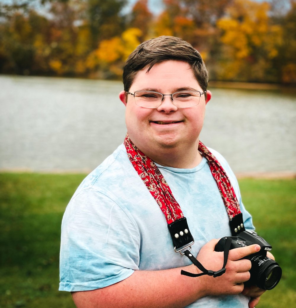  Houston smiling with a camera around his neck 