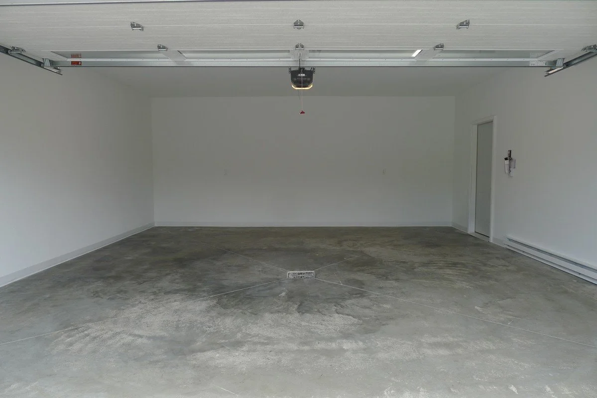 Empty garage with a concrete floor, white walls, and a closed garage door.