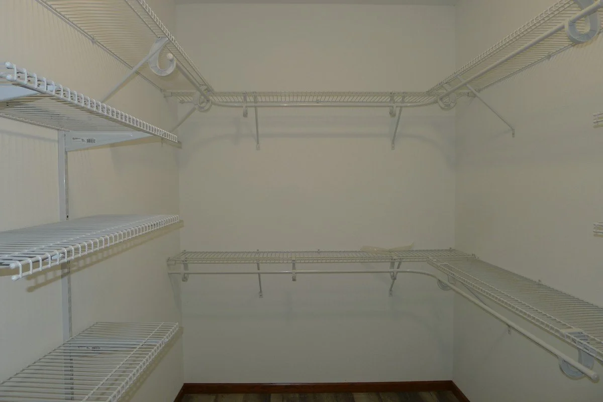 Empty walk-in closet with white wire shelves on all walls.