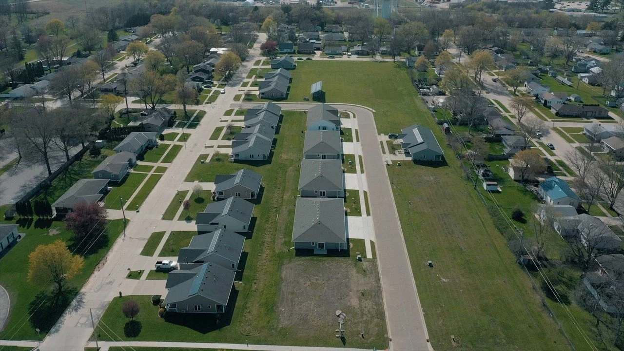 Aerial view of a residential neighborhood with single-family homes, streets, and green lawns.