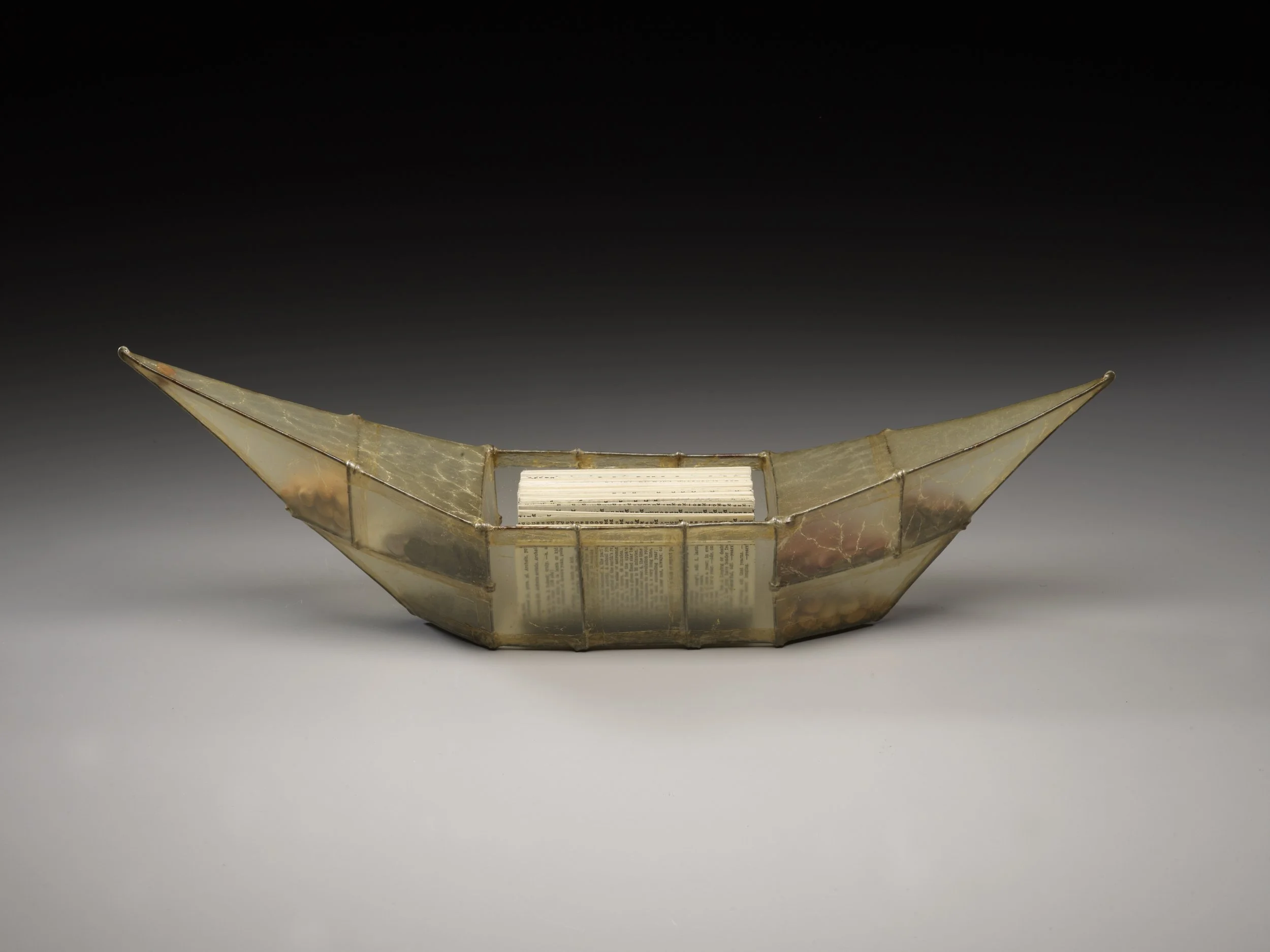 a vessel made of steel wire with a skin of hog gut, there are seeds in the compartments of the bow and stern and a Coptic bound book made of antique dictionary pages in the cockpit