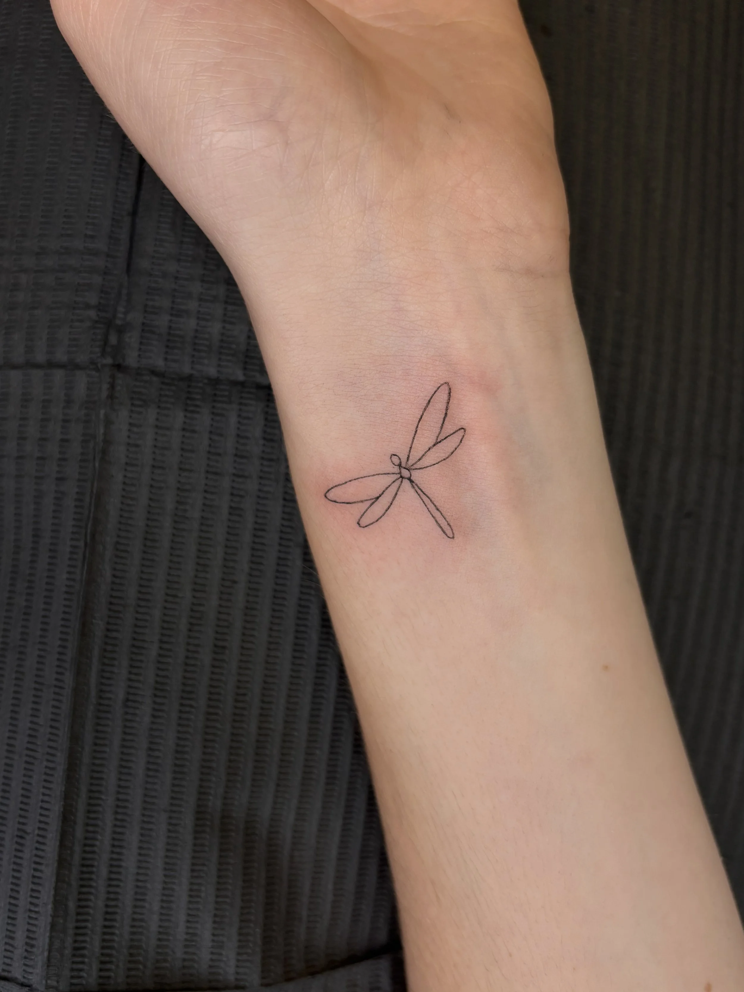 A tattoo of a dragonfly outline done by Brooke Kalynn