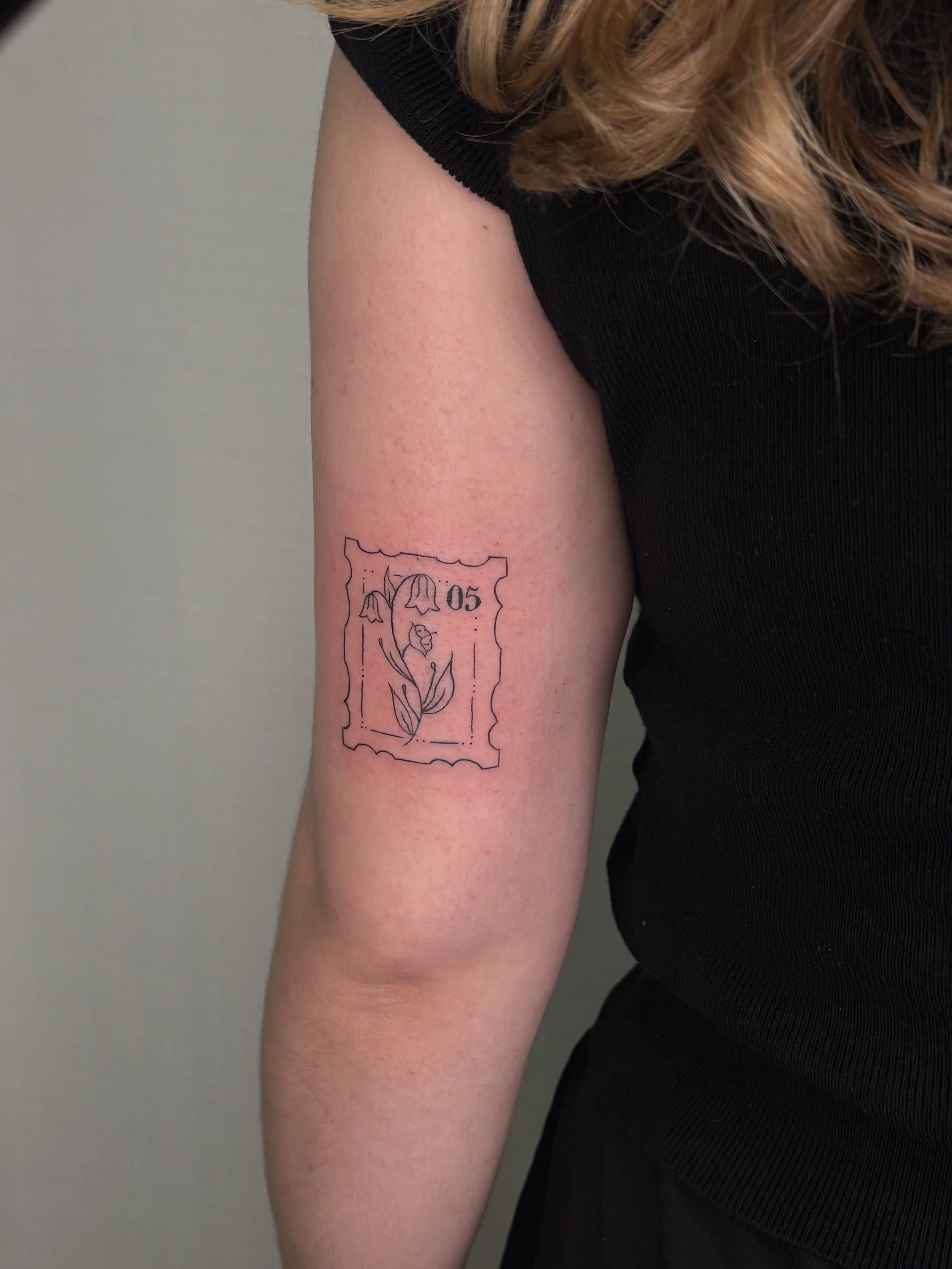 A tattoo of a stamp with a flower done by Brooke Kalynn