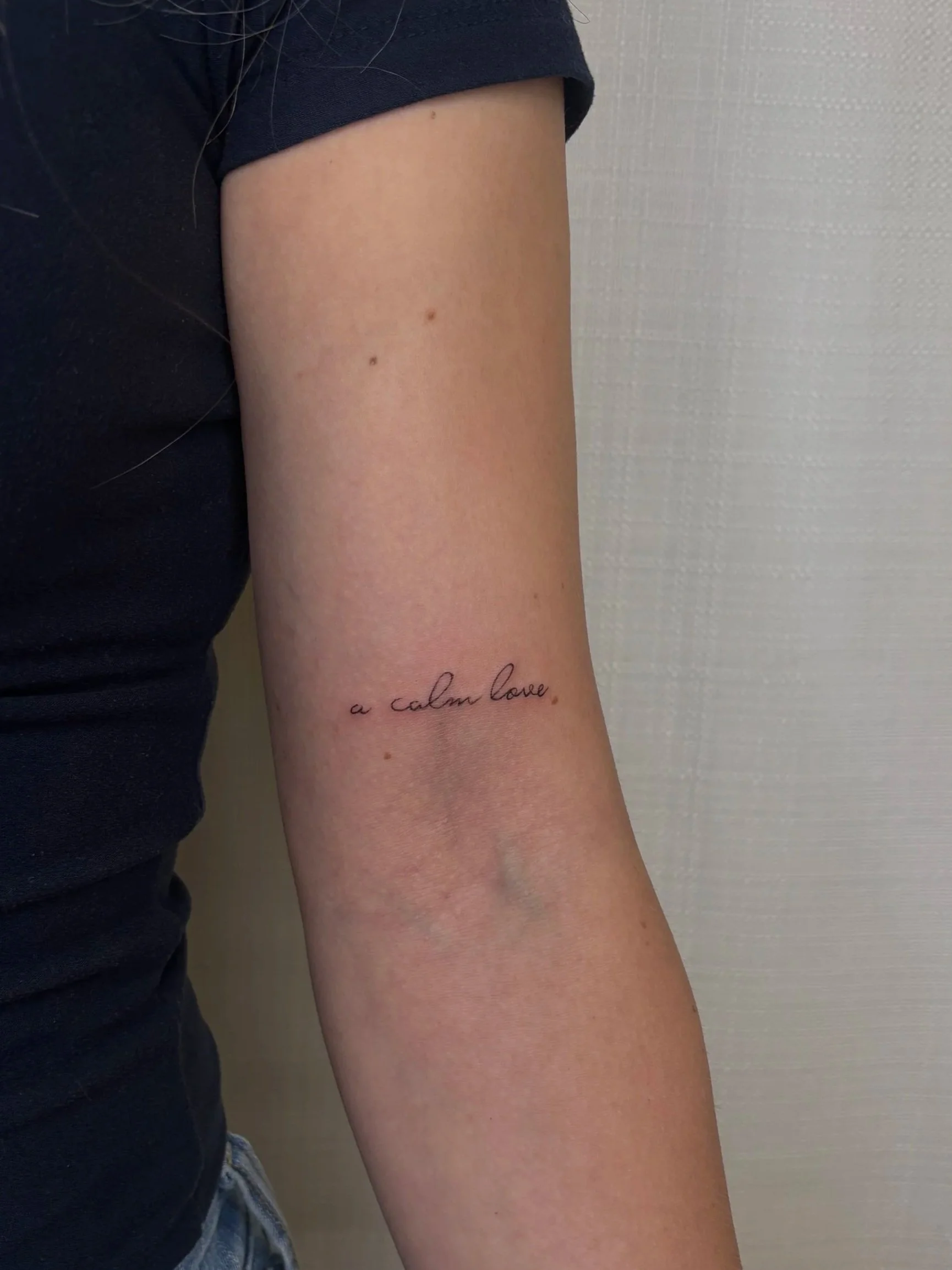 A tattoo of a quote that says "a calm love" done by Brooke Kalynn
