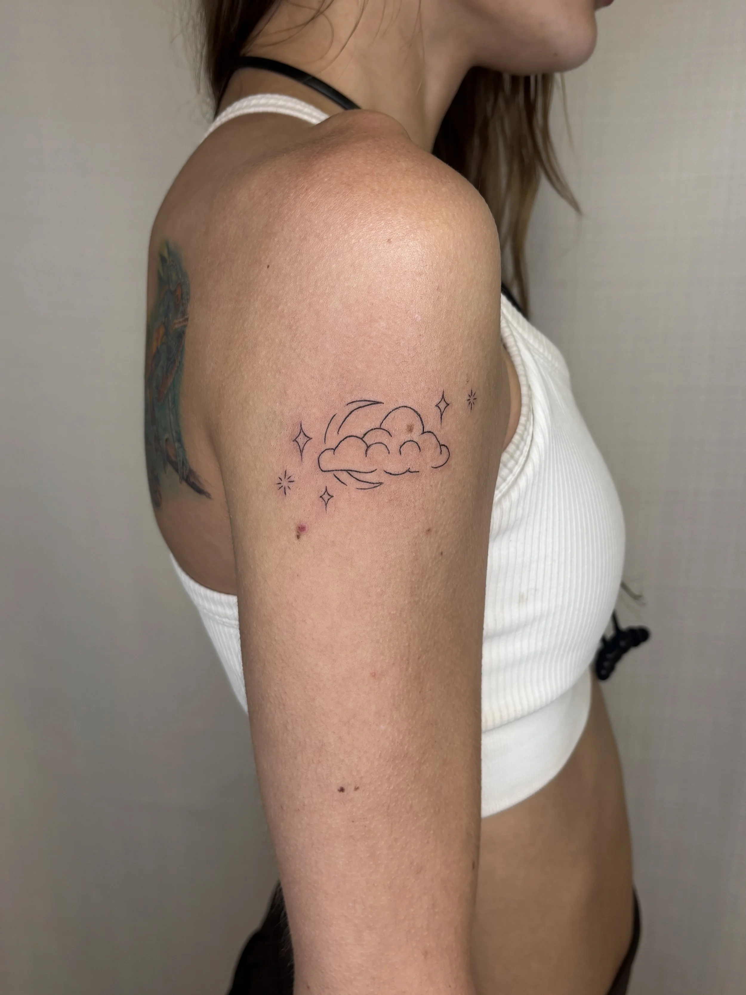 A tattoo of a cloud, moon and ornamentals done by Brooke Kalynn