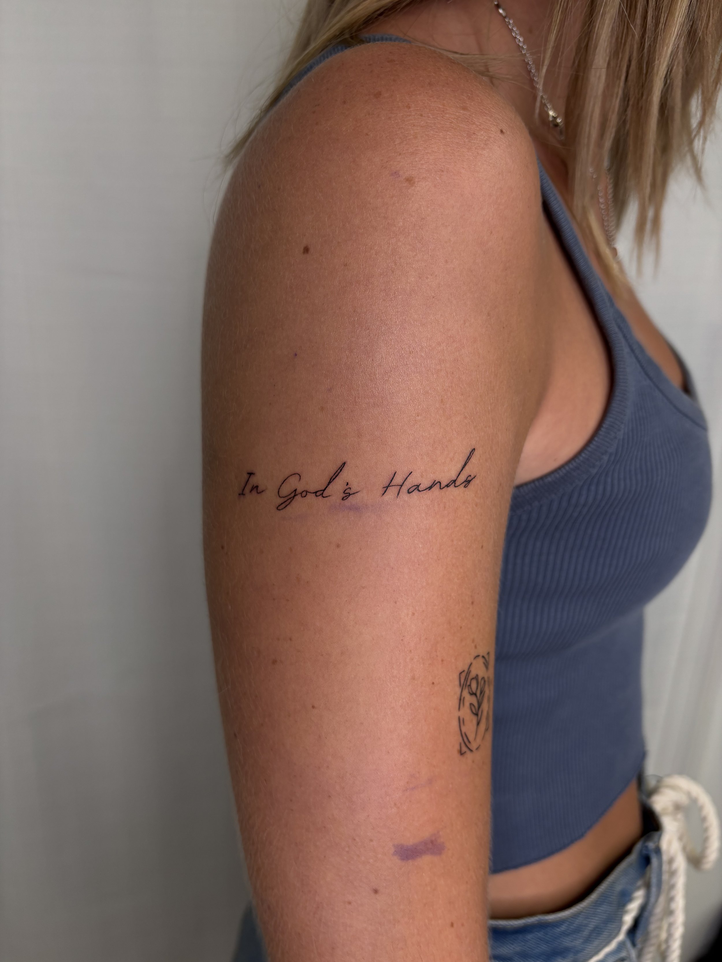 A tattoo that says "In God's Hands" done by Brooke Kalynn