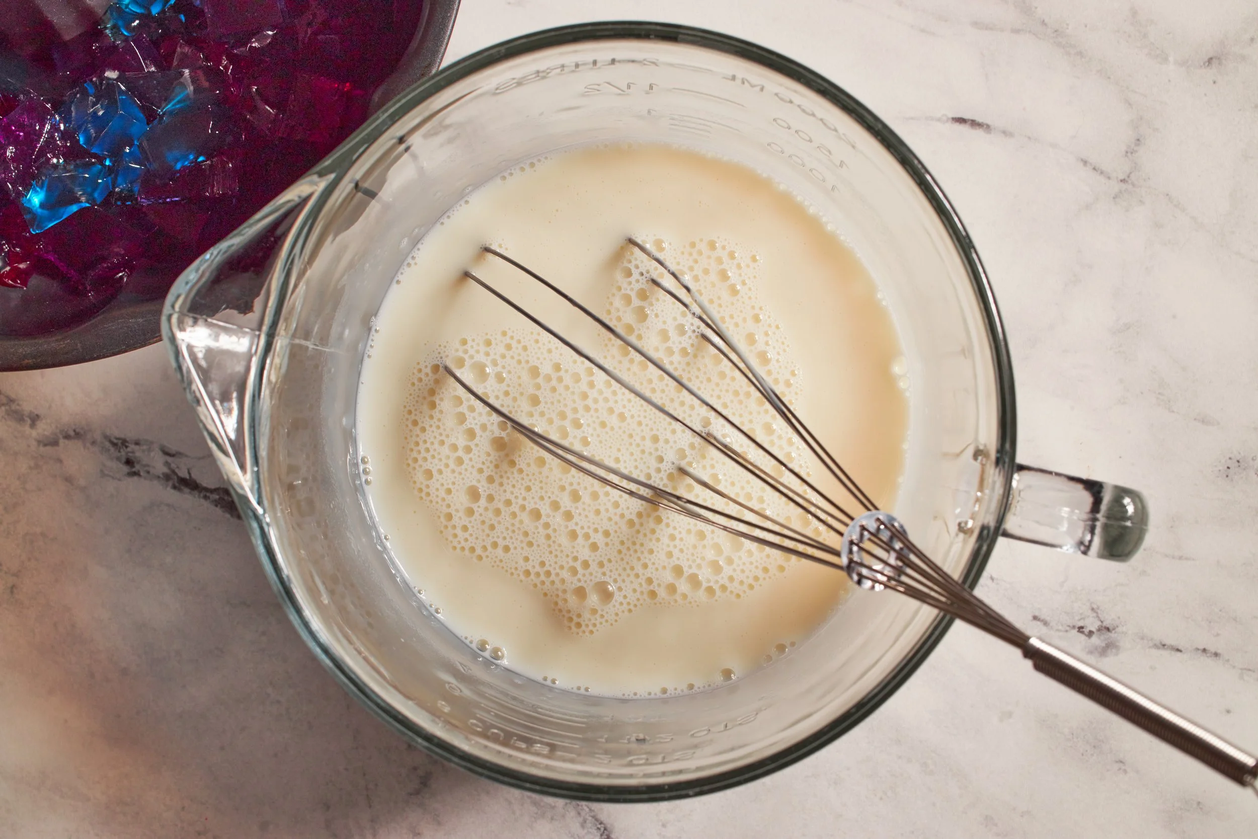 gelatin mixed with sweetened condensed milk in a mixing bowl with whisk