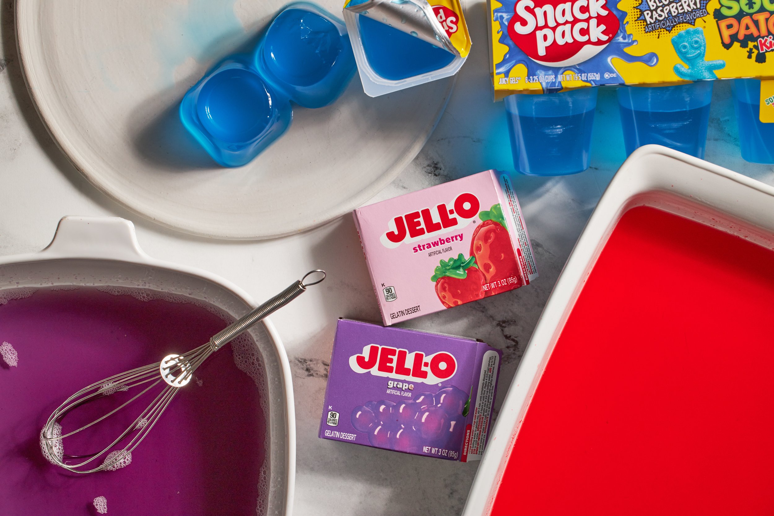 boxes of strawberry jello grape jello blue jello in baking dish for broken jello dessert jessica furniss