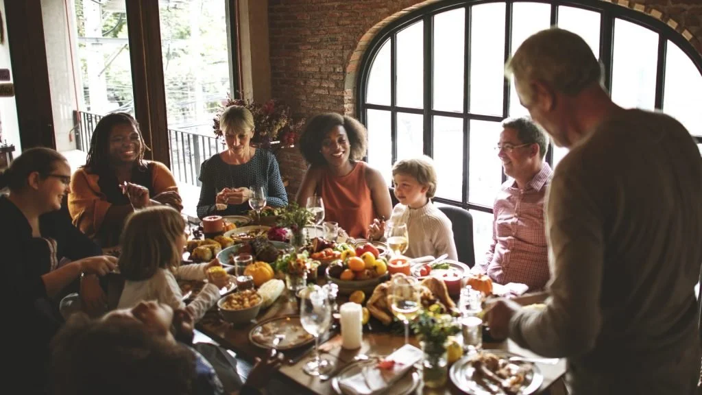 Mixed family sitting around the dinner table celebrating the holidays - Attuned Families