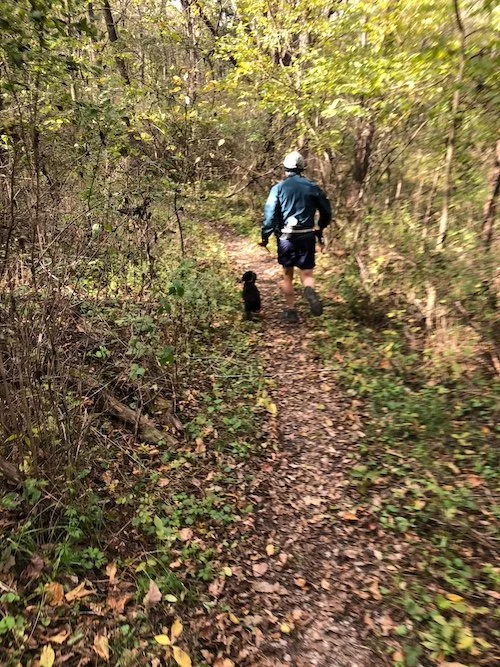 Runner with a dog on a singletrack trail.