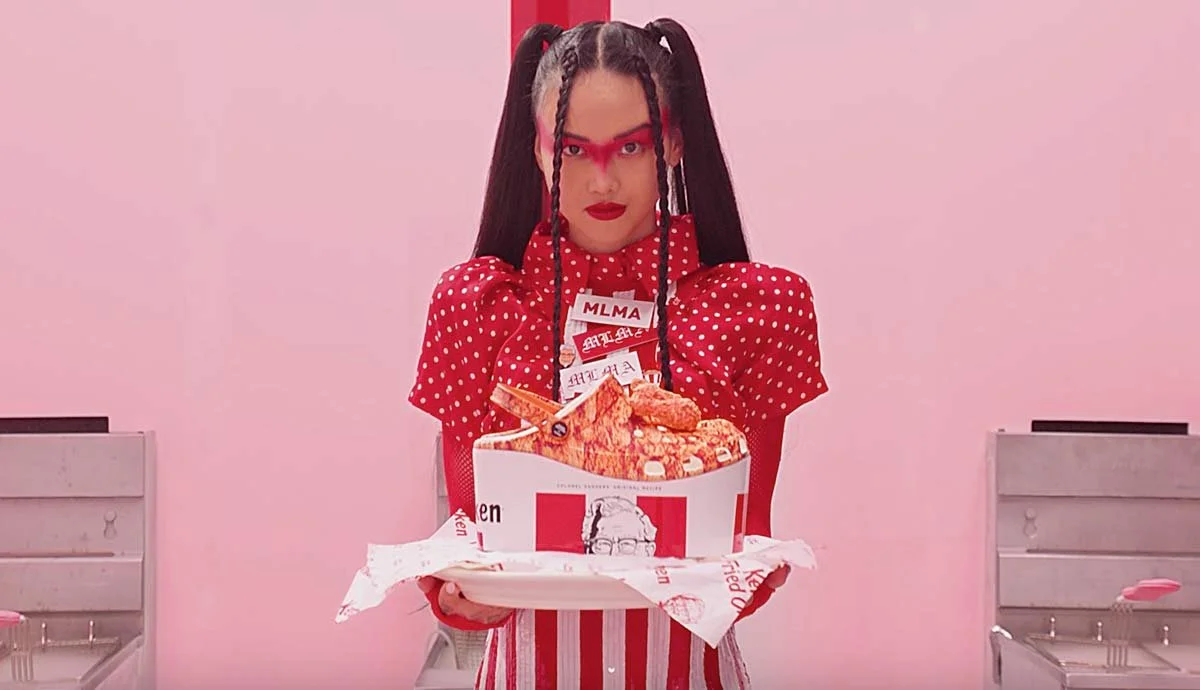 A woman dressed in a red polka dot dress holding a tray with fried chicken fast food.