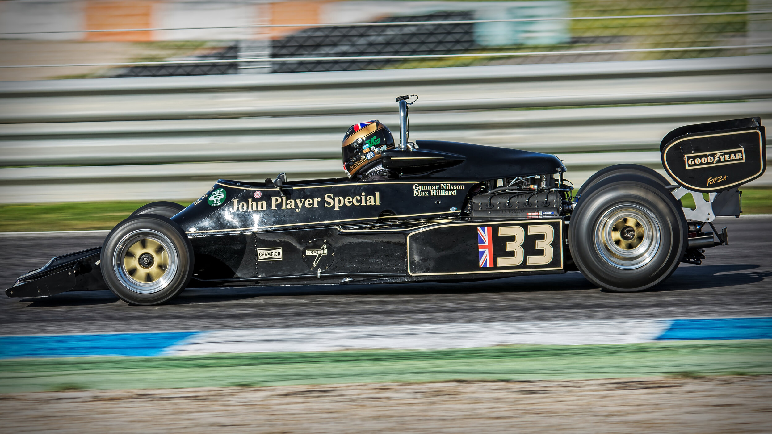 Vintage black and gold Formula 1 car with John Player Special livery, number 33, racing on a track.