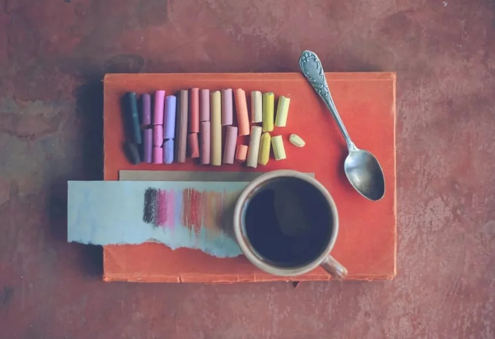 Colored chalk and a teacup on an orange table