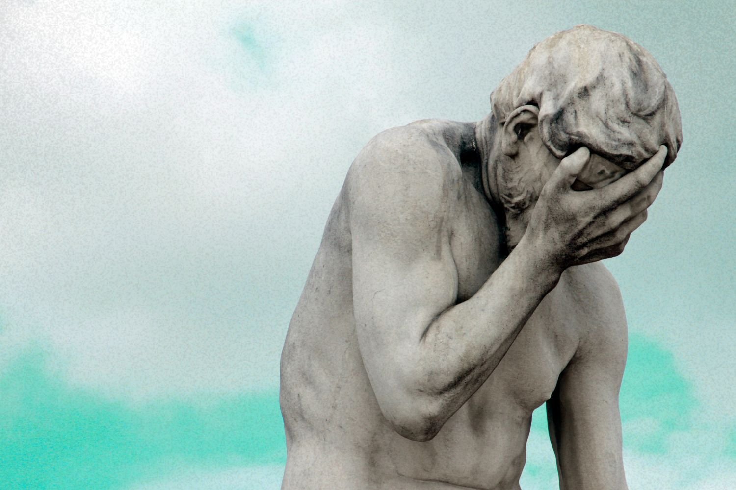 Statue with head in hand against a turquoise sky, symbolizing neurodivergent shutdown.