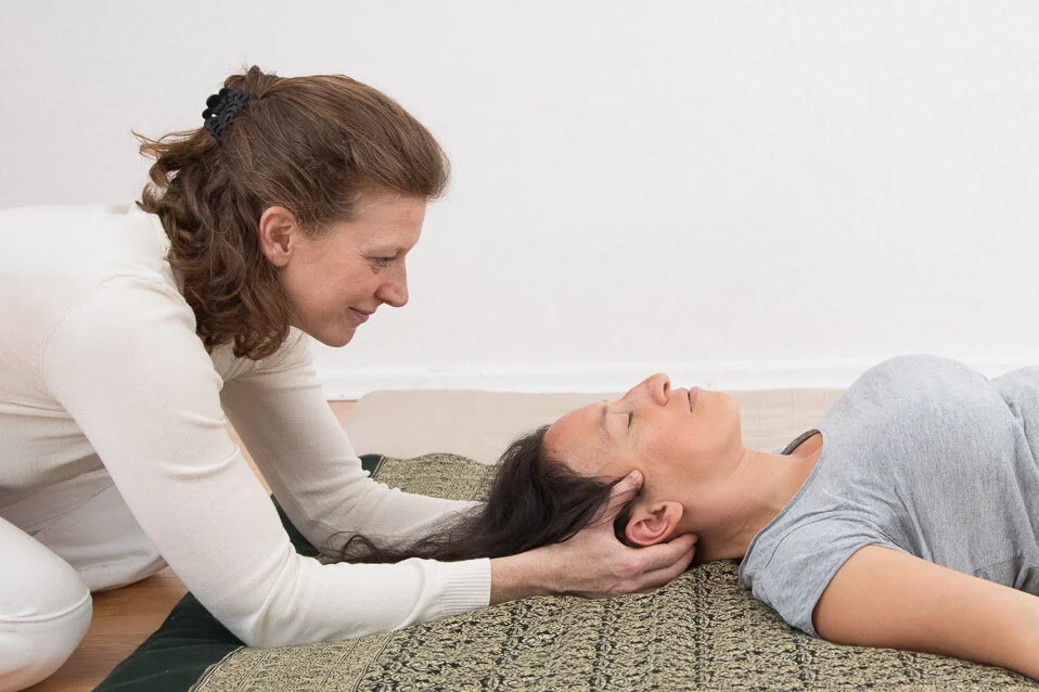 Barbara Naur bei einer Nackenmassage in Rückenlage. Nacken und Kopfbehandlungen einer Shiatsu-Behandlung können Druckkopfschmerz, Verspannungen im Nacken und Kieferverspannungen bei Bruxismus lösen.