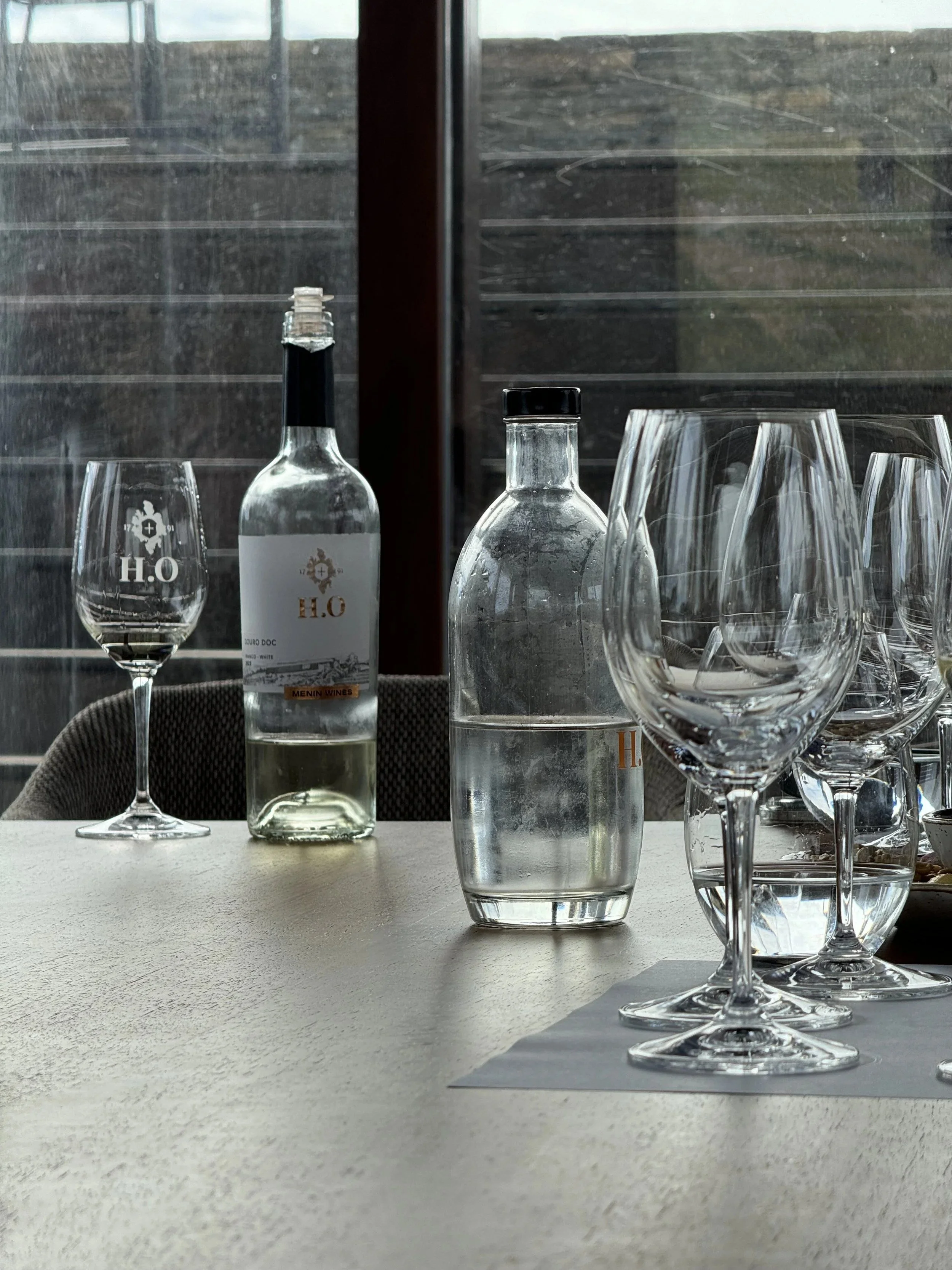 Wine glasses and a bottle set for a tasting at H.O. Winery in Cumieira.