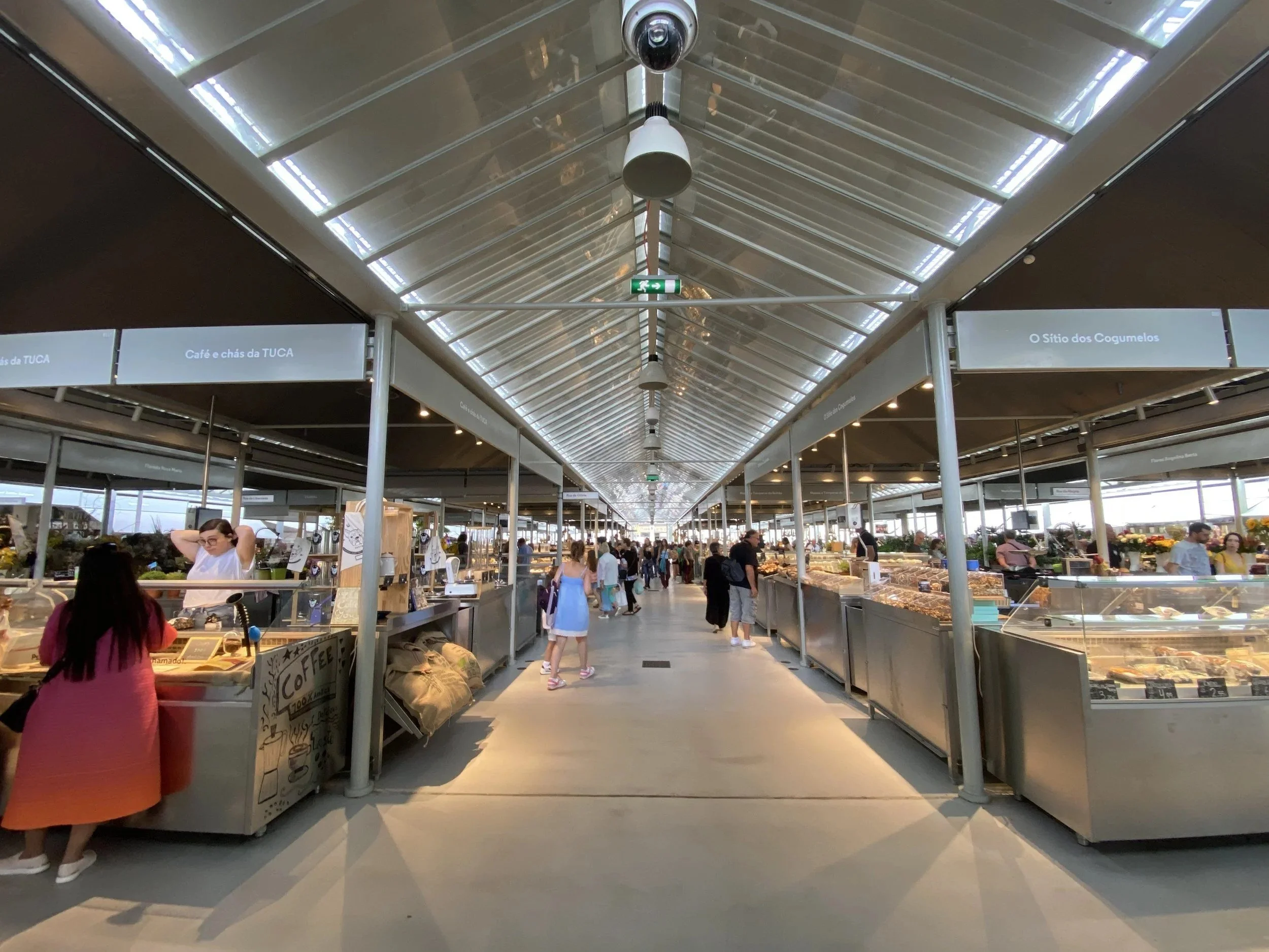 Market stalls under a long glass roof in central Porto.