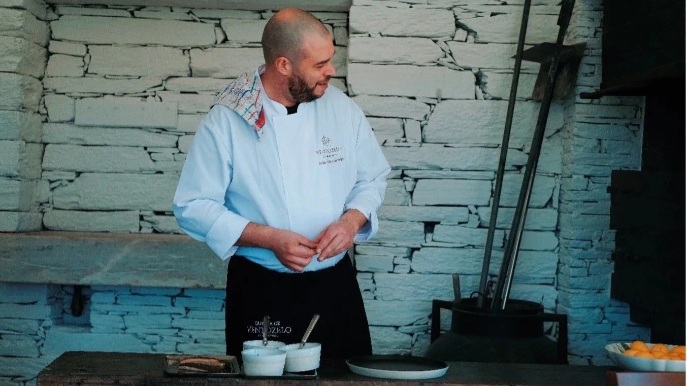 Chef João plating a dish in a stone-walled kitchen.