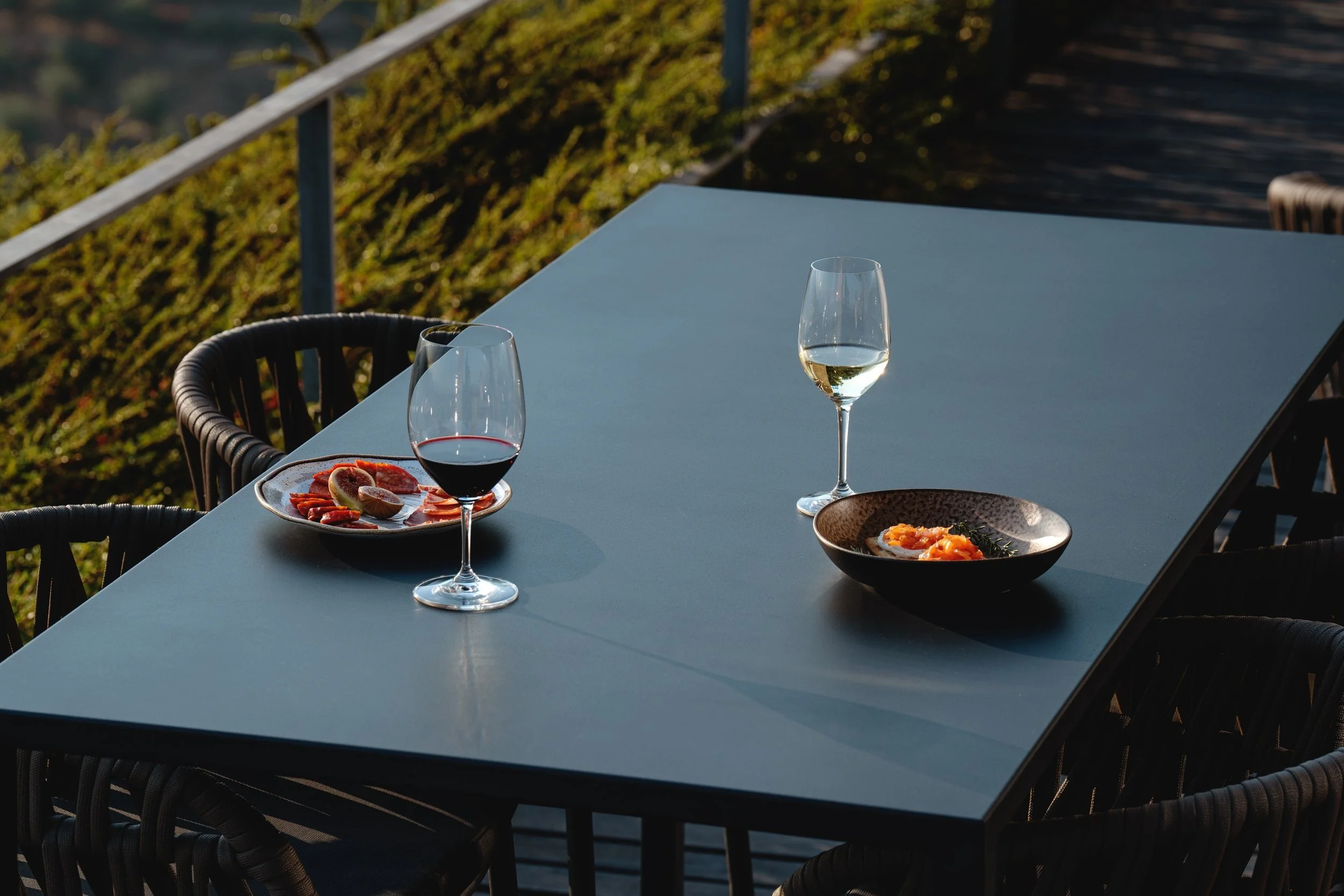 Glasses of red and white wine with a snack on a terrace table above the vineyards.