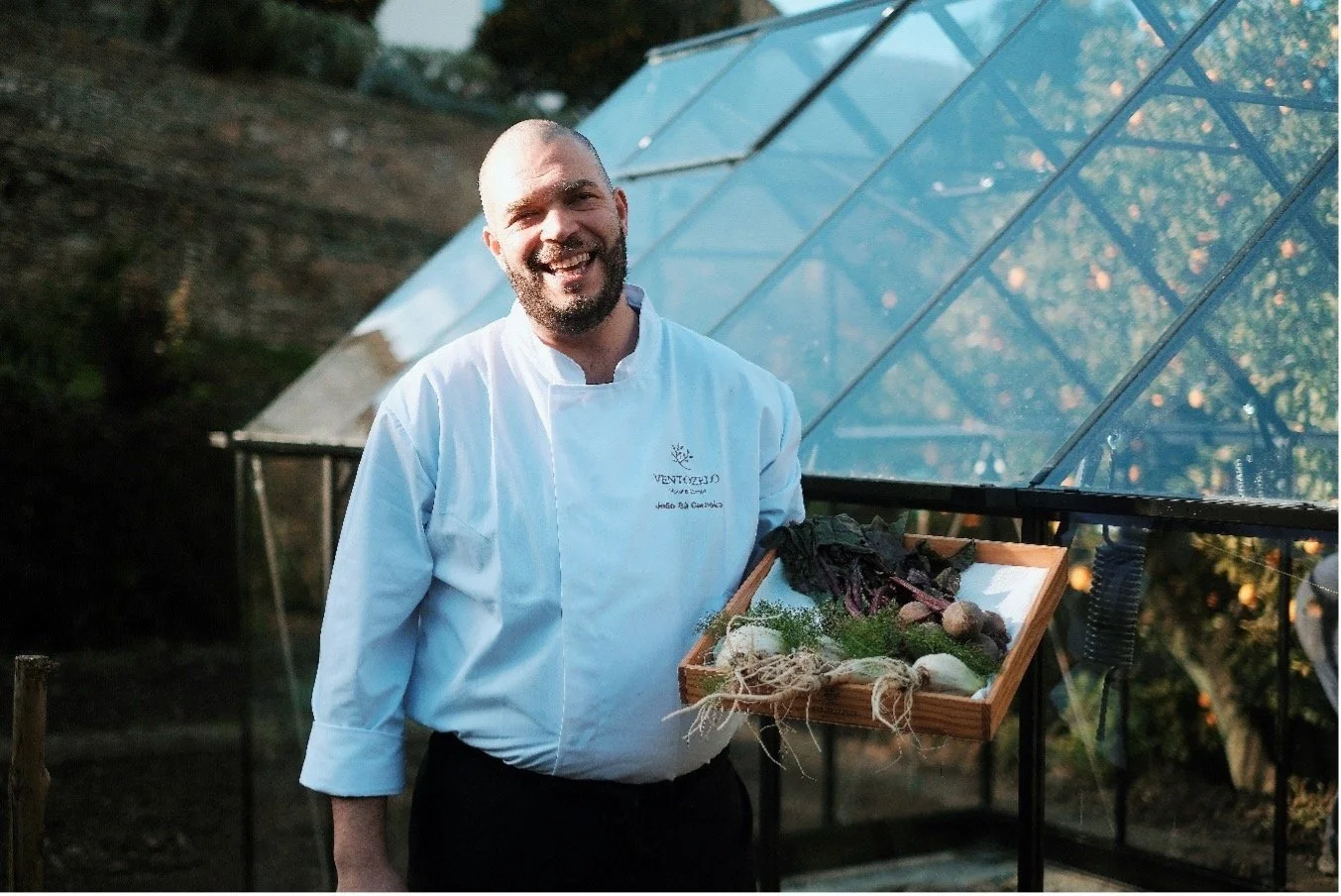 Chef João Sá Carneiro holding a tray of fresh produce from the garden.