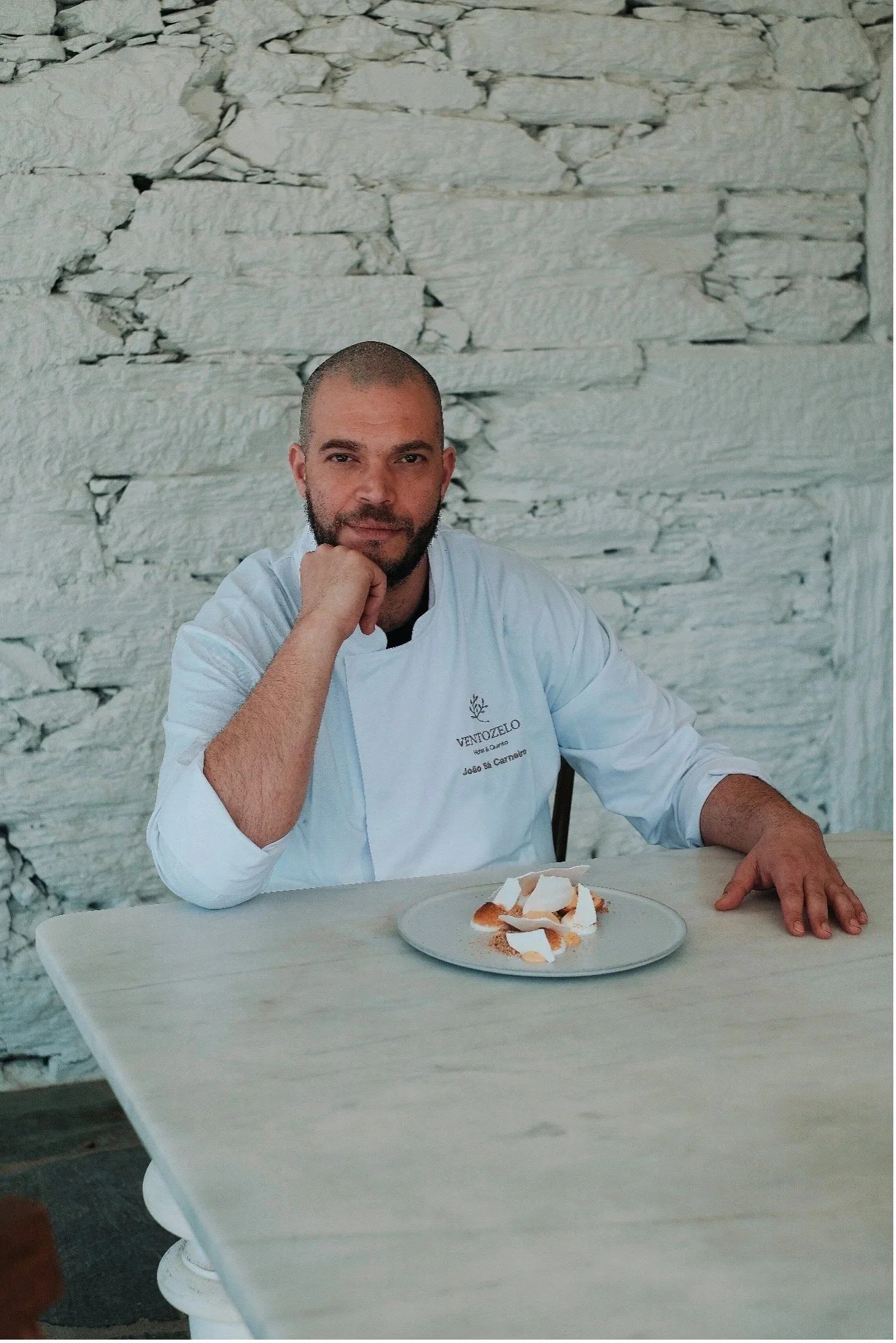 Chef João Sá Carneiro at a table in a whitewashed room.