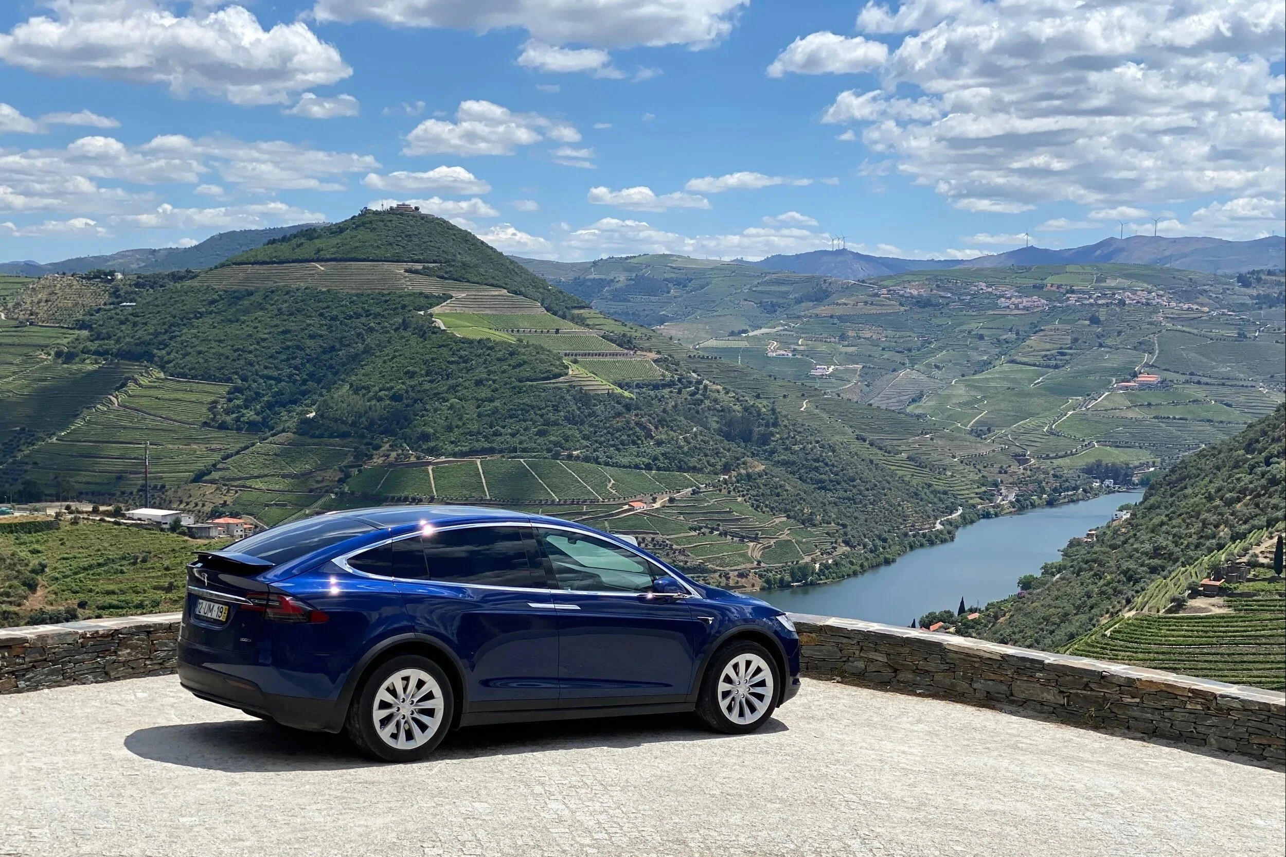 The blue Tesla parked at a Douro viewpoint above the river.