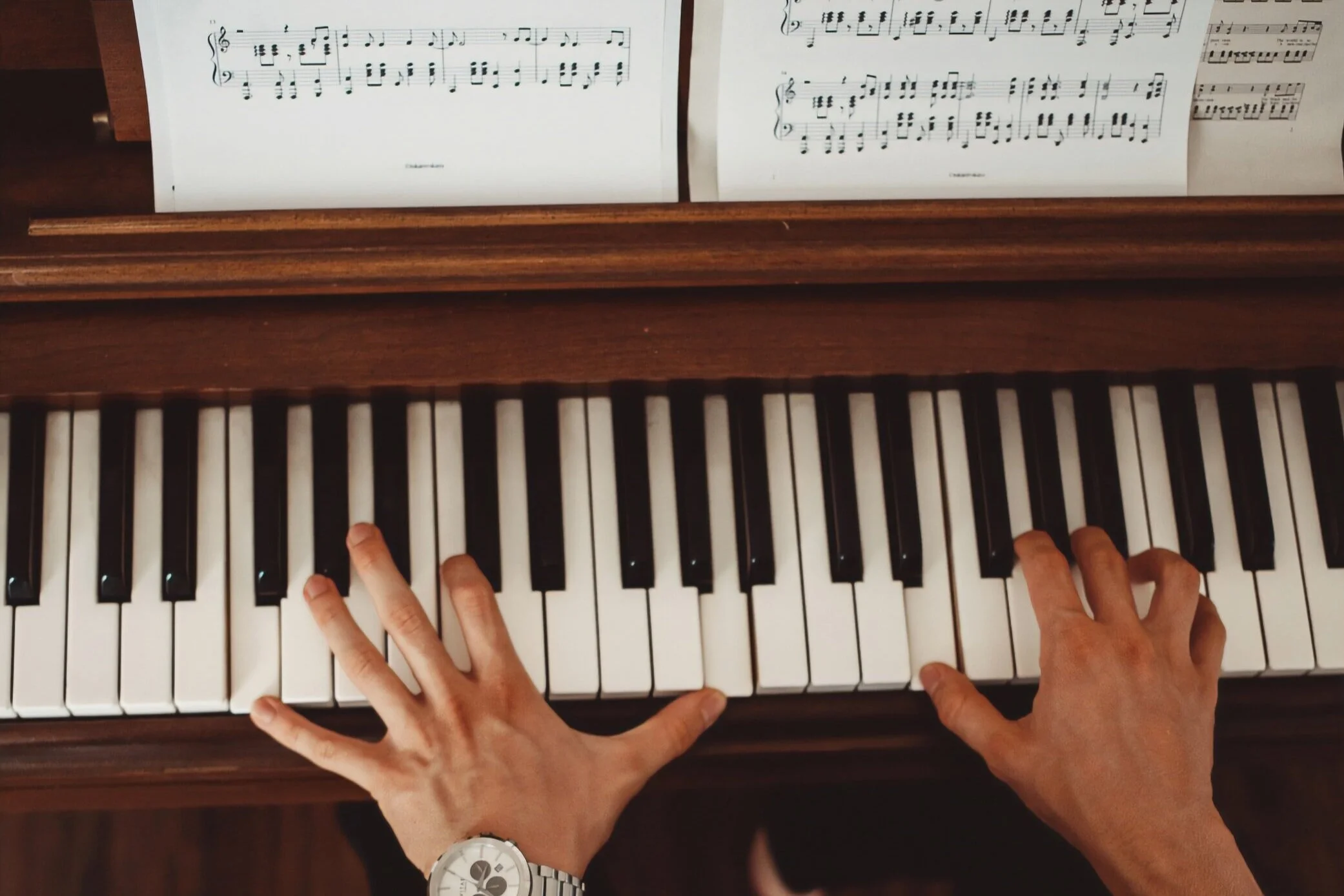 Hands practicing piano technique on an upright piano