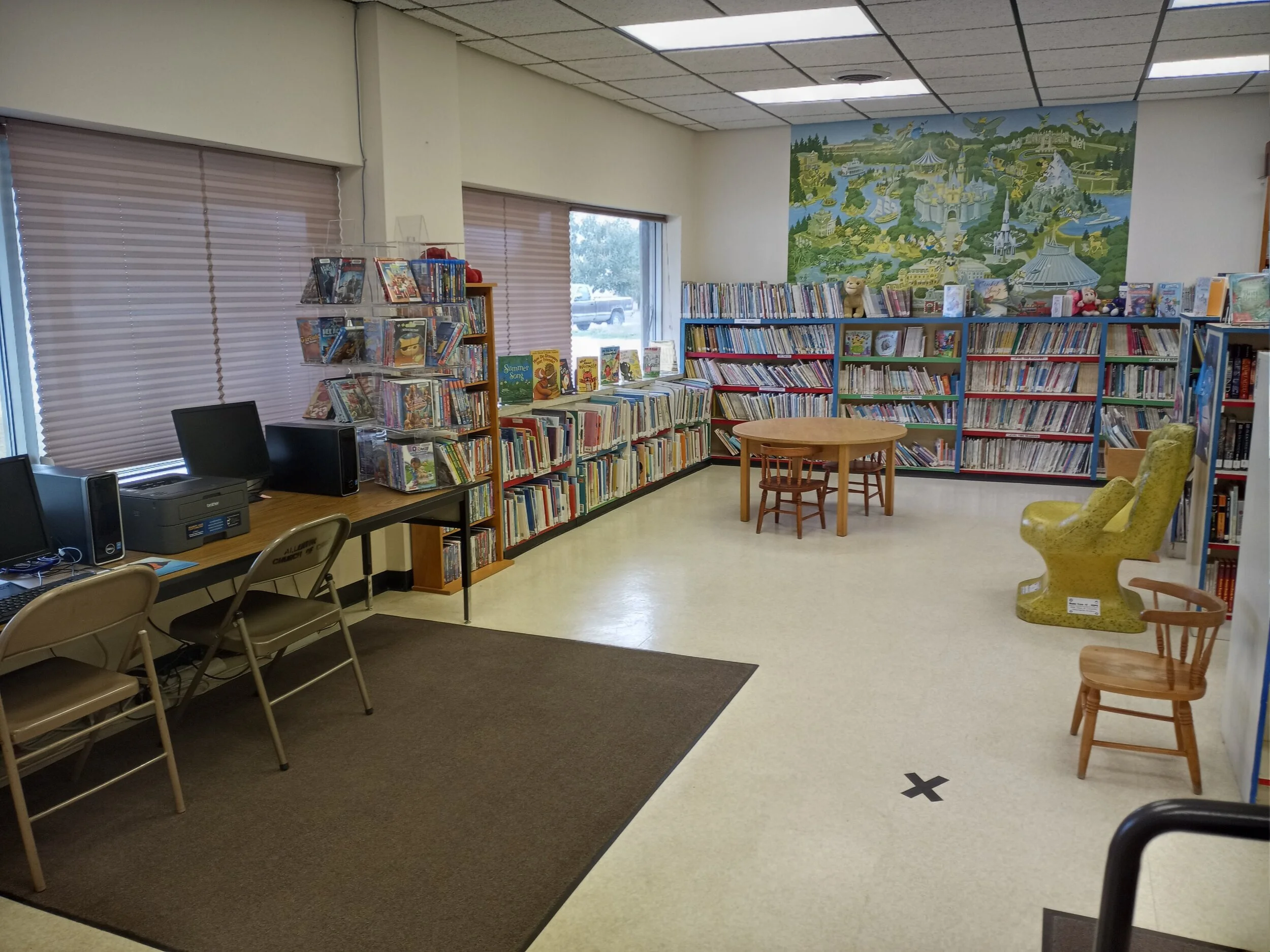 Kids section of book shelves with seating and available computers with printers