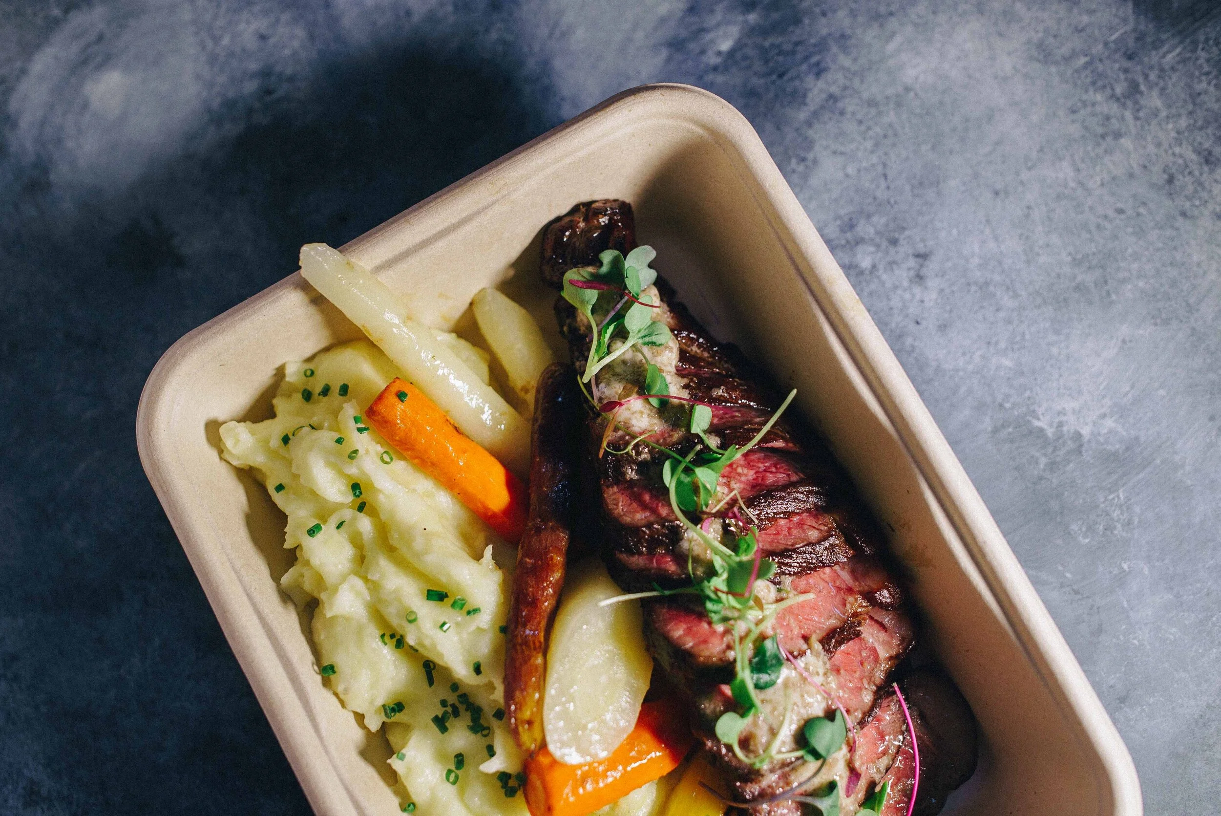 Meal tray with steak, mashed potatoes, and vegetables