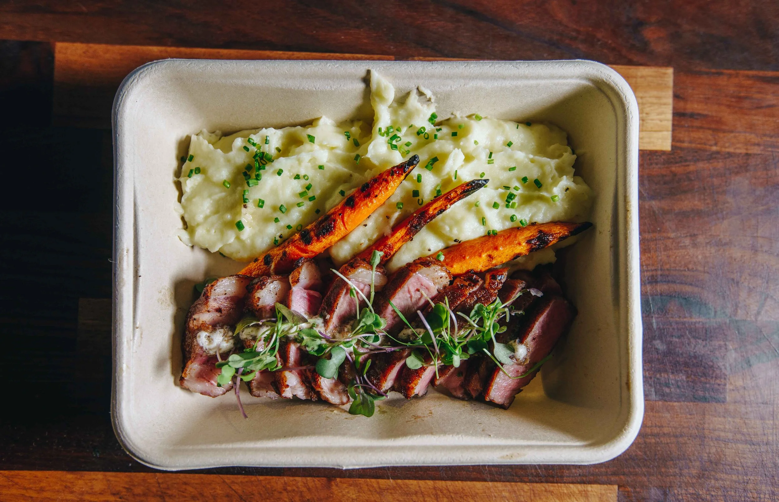 Meal tray with sliced meat, mashed potatoes, and roasted carrots