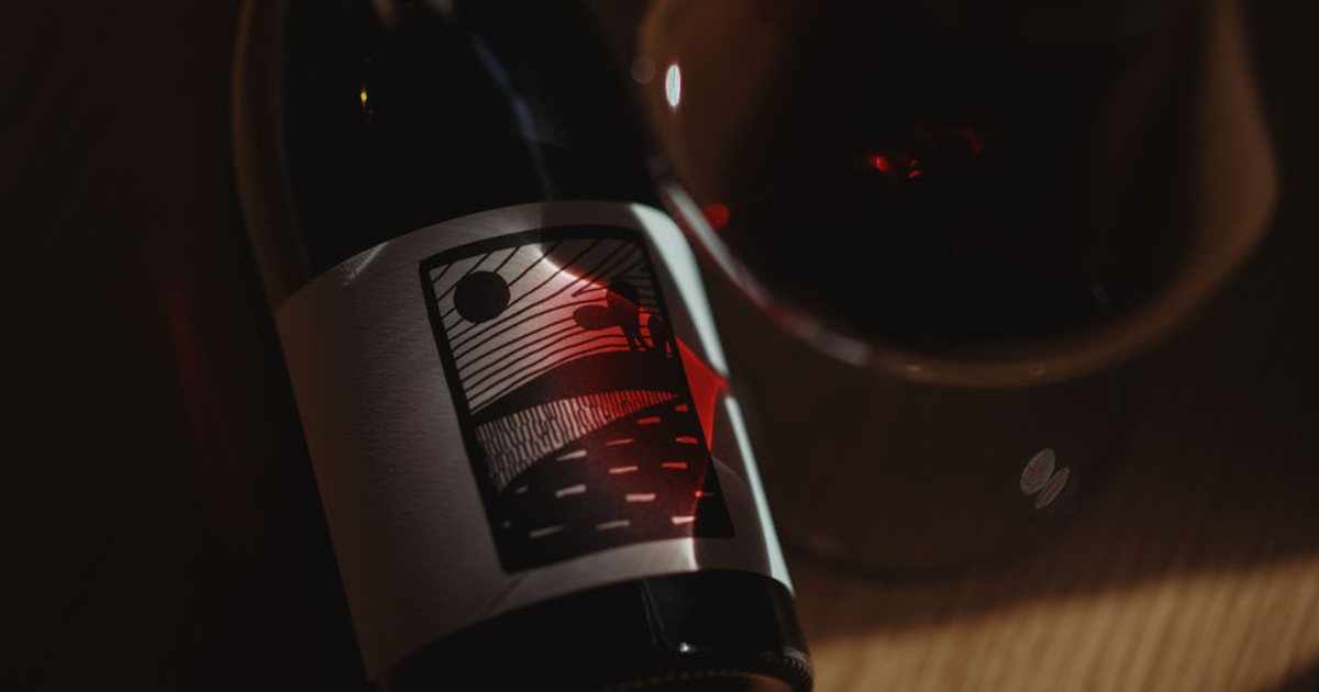Bottle of Tasmanian Pinot Noir on table with red wine reflected on the label.