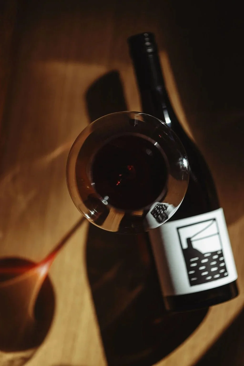 Image of a bottle of sonnen pinot noir on a wooden table with black and white label artwork by Tasmanian artist Harriet Wilson.