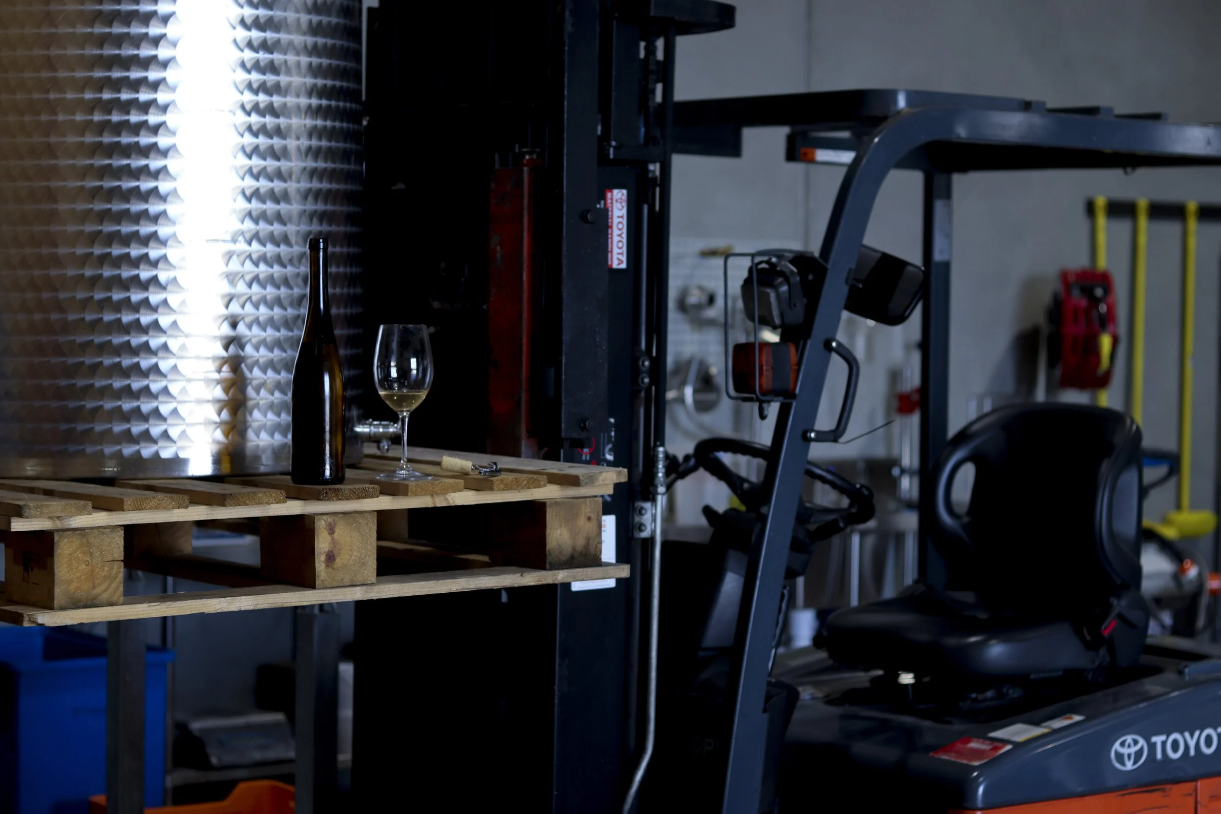 A bottle of Riesling sits atop a pallet held up by a forklift in a winery