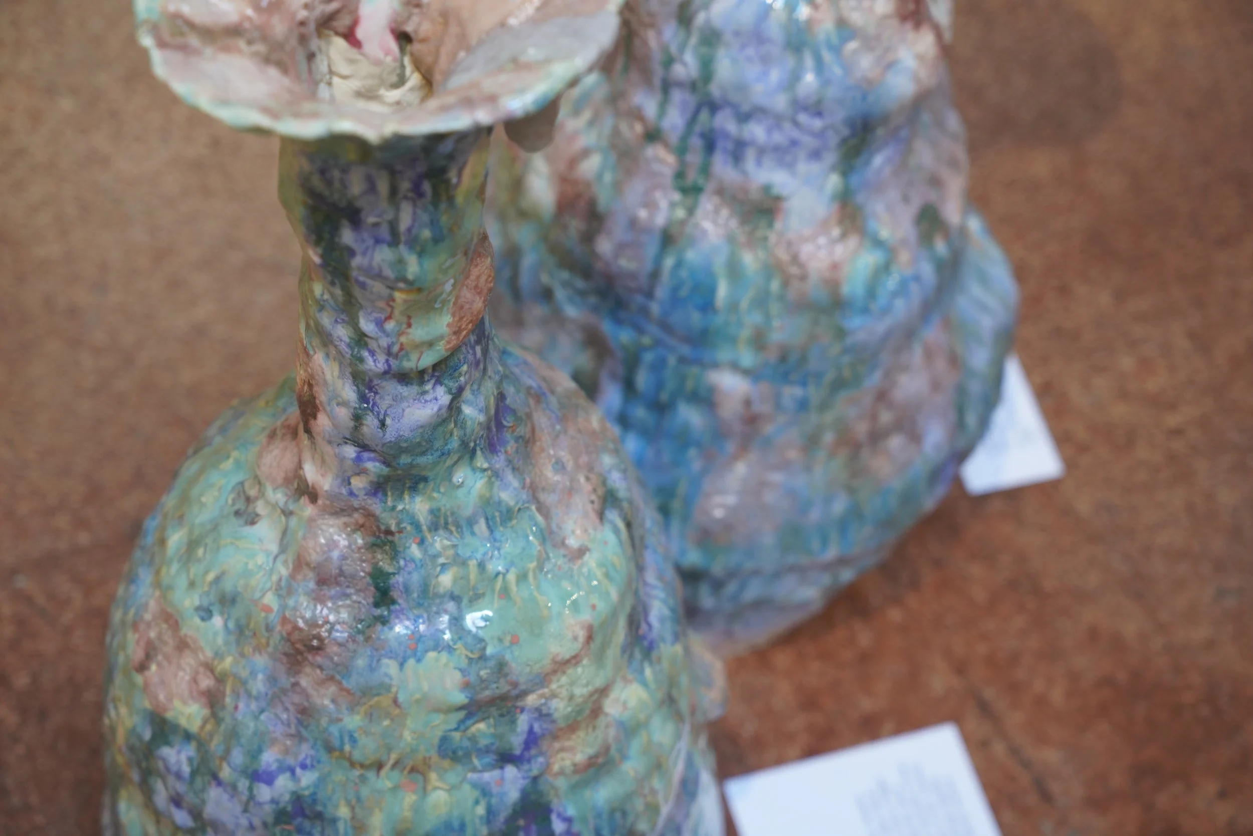 Close-up of a colorful, abstract sculpture or artwork made with textured, layered materials and painted with multicolored, iridescent paint.