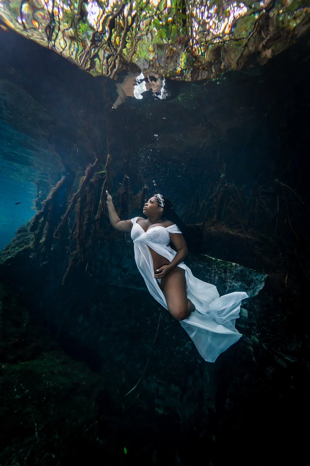 A woman posing for an Underwater Maternity photoshoot