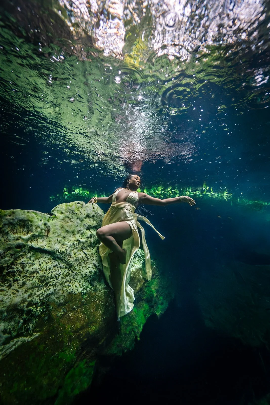An African American woman posing for an underwater photoshoot in a Mexican cenote
