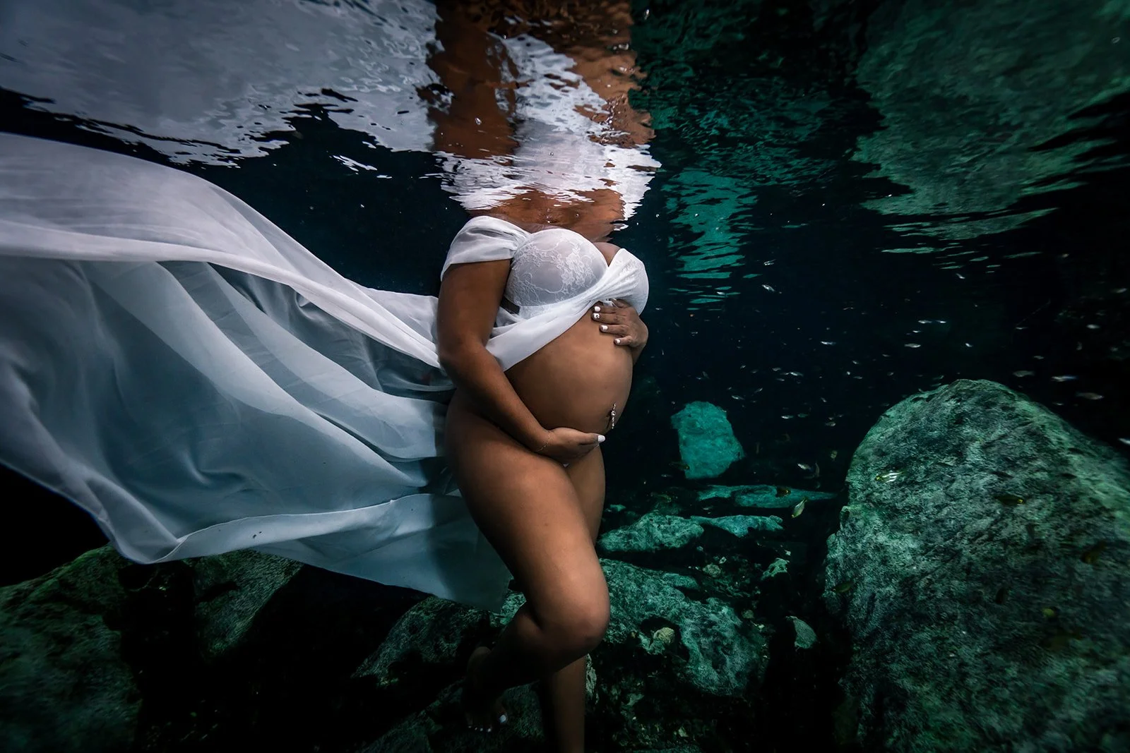An African American pregnant woman posing in Cancun for a Maternity underwater photography session