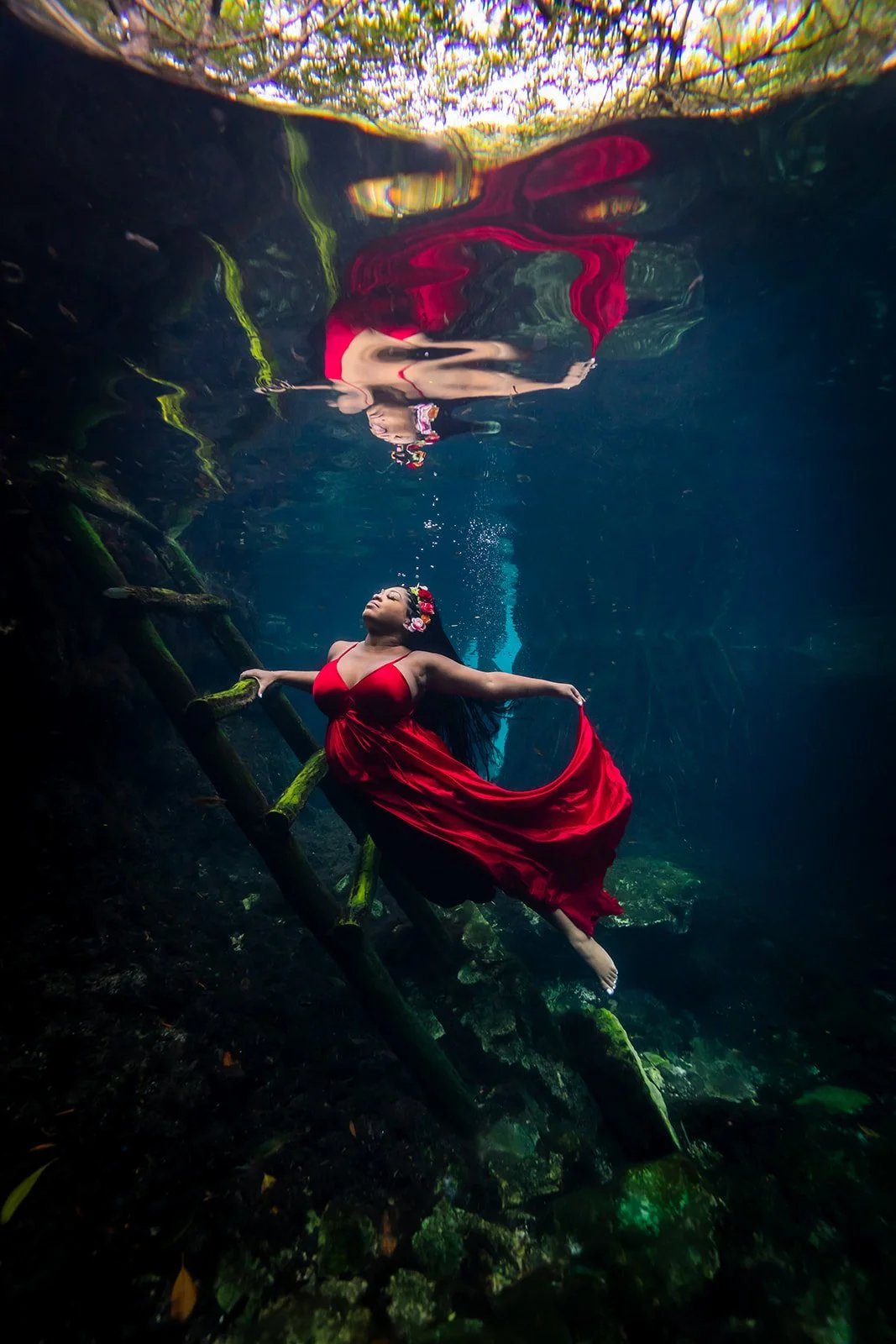 An African american woman in a red dress posing for cenote a Underwater photography