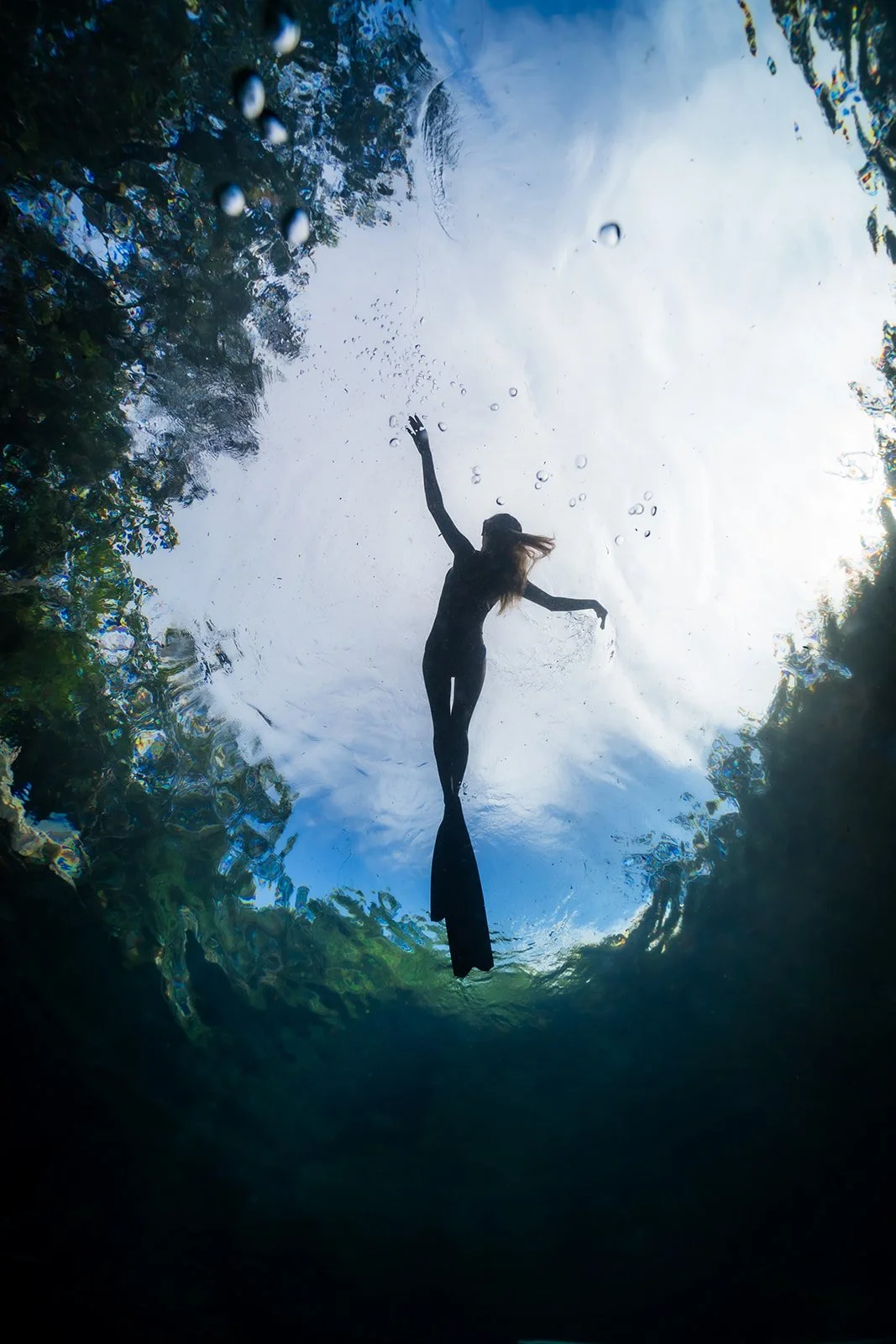 A woman swimming with fins in a crystal clear cenote close to Playa del Carmen