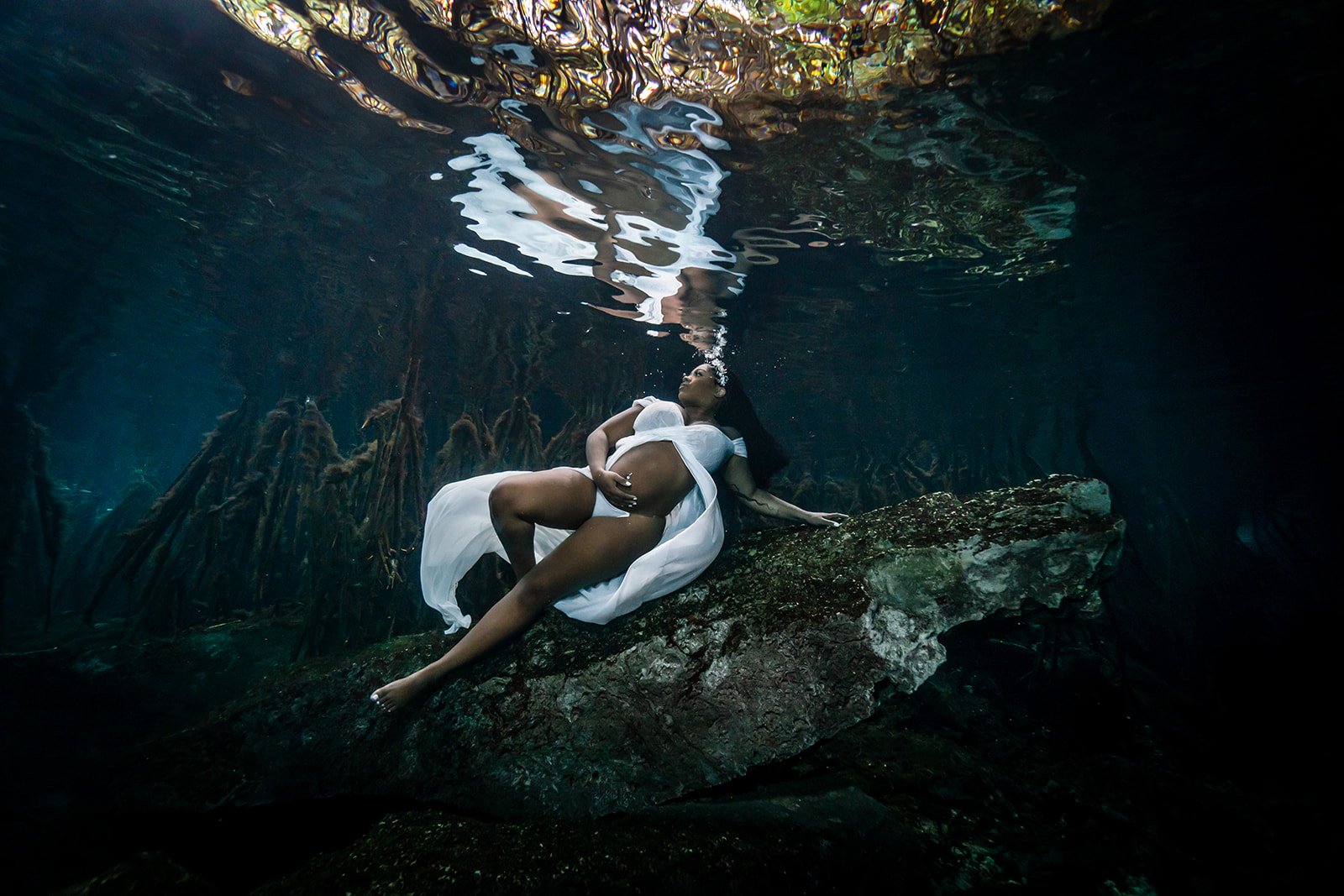 An African American pregnant woman posing in a dress for a Maternity Underwater photoshoot in Riviera Maya