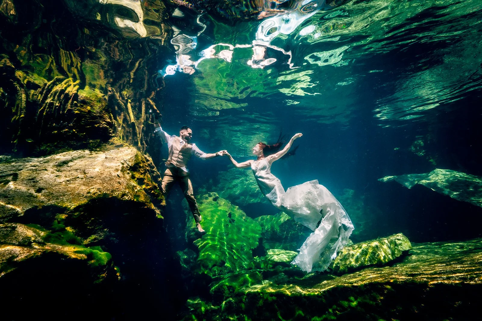 Couple posing for a trash the dress photoshoot in a cenote in Tulum