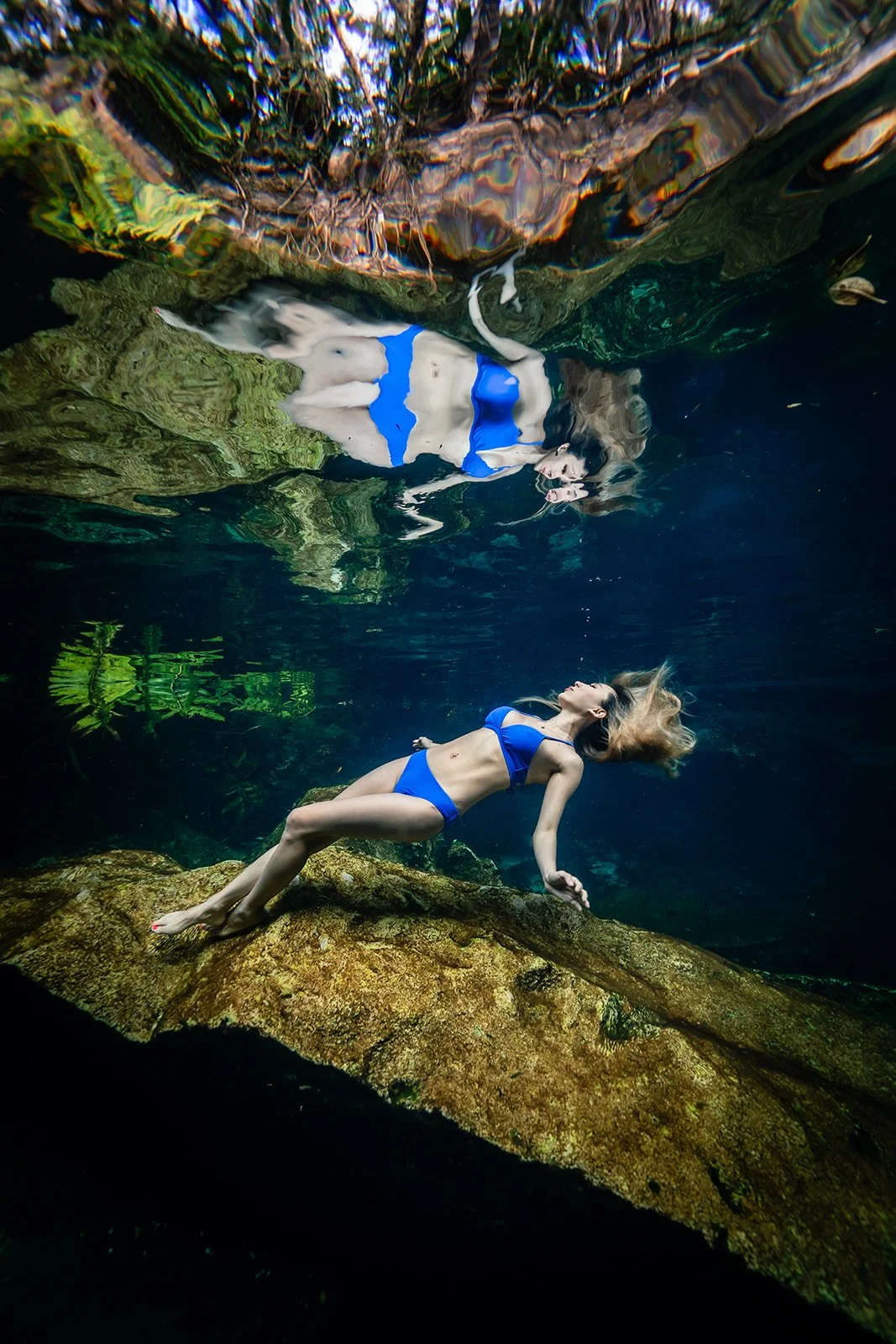 A woman in a blue swimsuit posing in a cenote protrait in Cancun