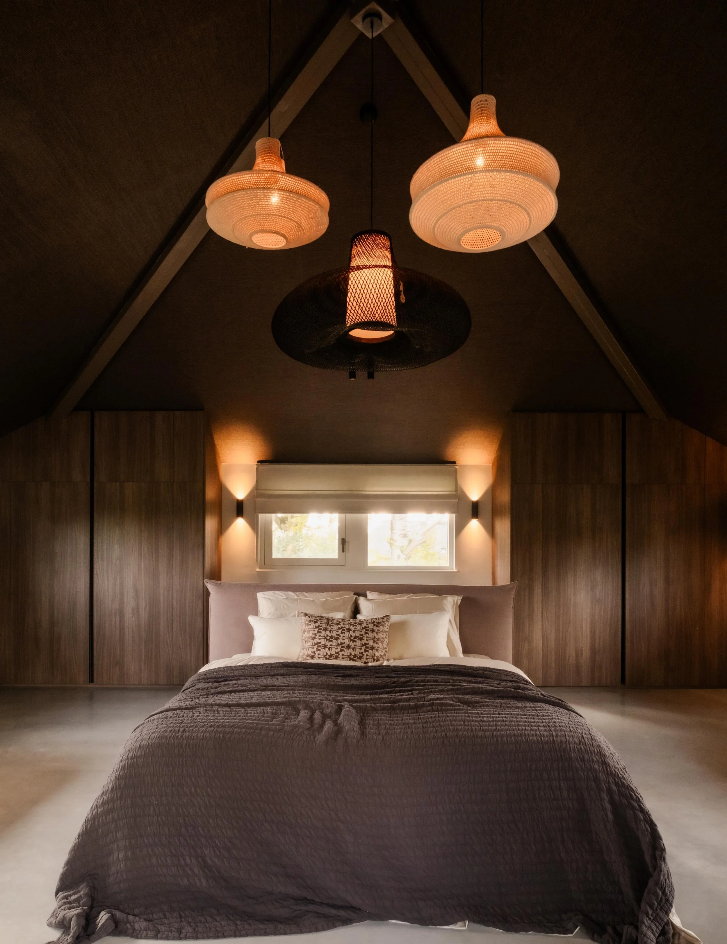 | HOOGTE ALS KRACHT 

Een ruimte met veel hoogte voelt indrukwekkend, maar vraagt ook om aandacht voor sfeer en geborgenheid. In deze slaapkamer hebben we daarom niet alleen de wanden, maar ook het plafond betrokken in het ontwerp. Het behang van nat