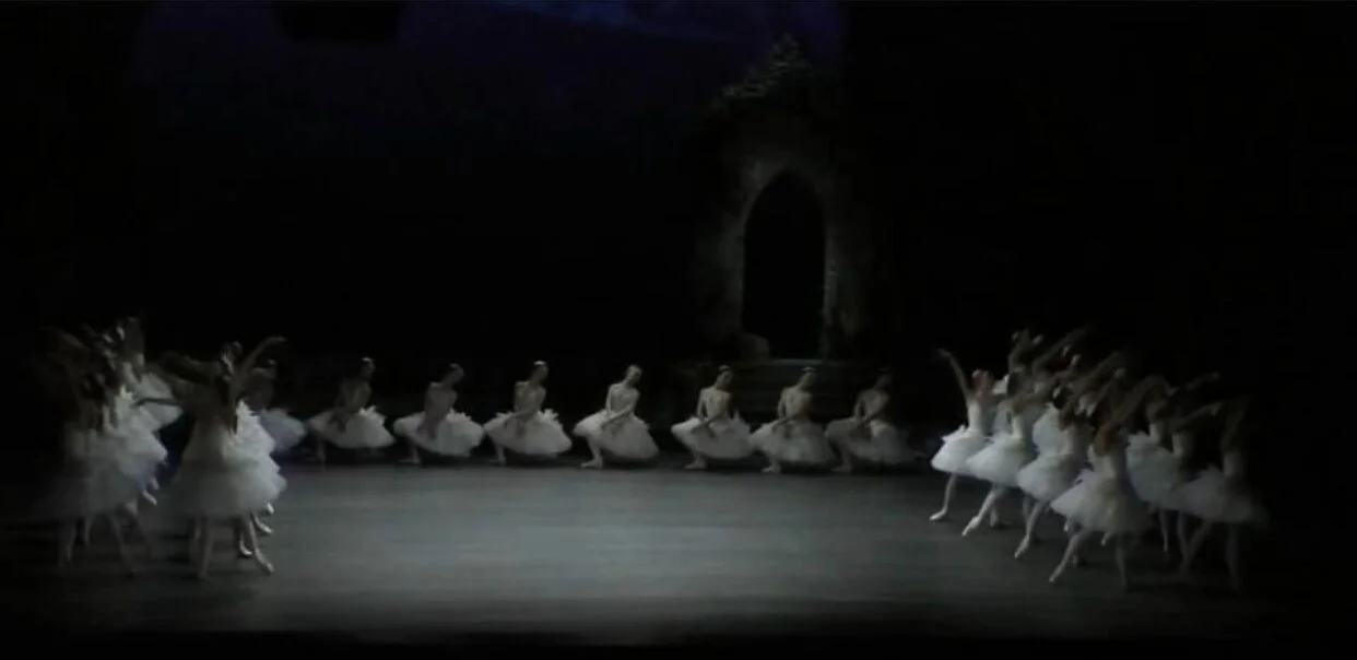 On either side of the stage, the swan-maiden corps now contributes characteristic steps: here off point and asymmetrical, in tendu side. First night of Alexei Ratmansky’s 2016 production of “Swan Lake”, Zürich Ballet.