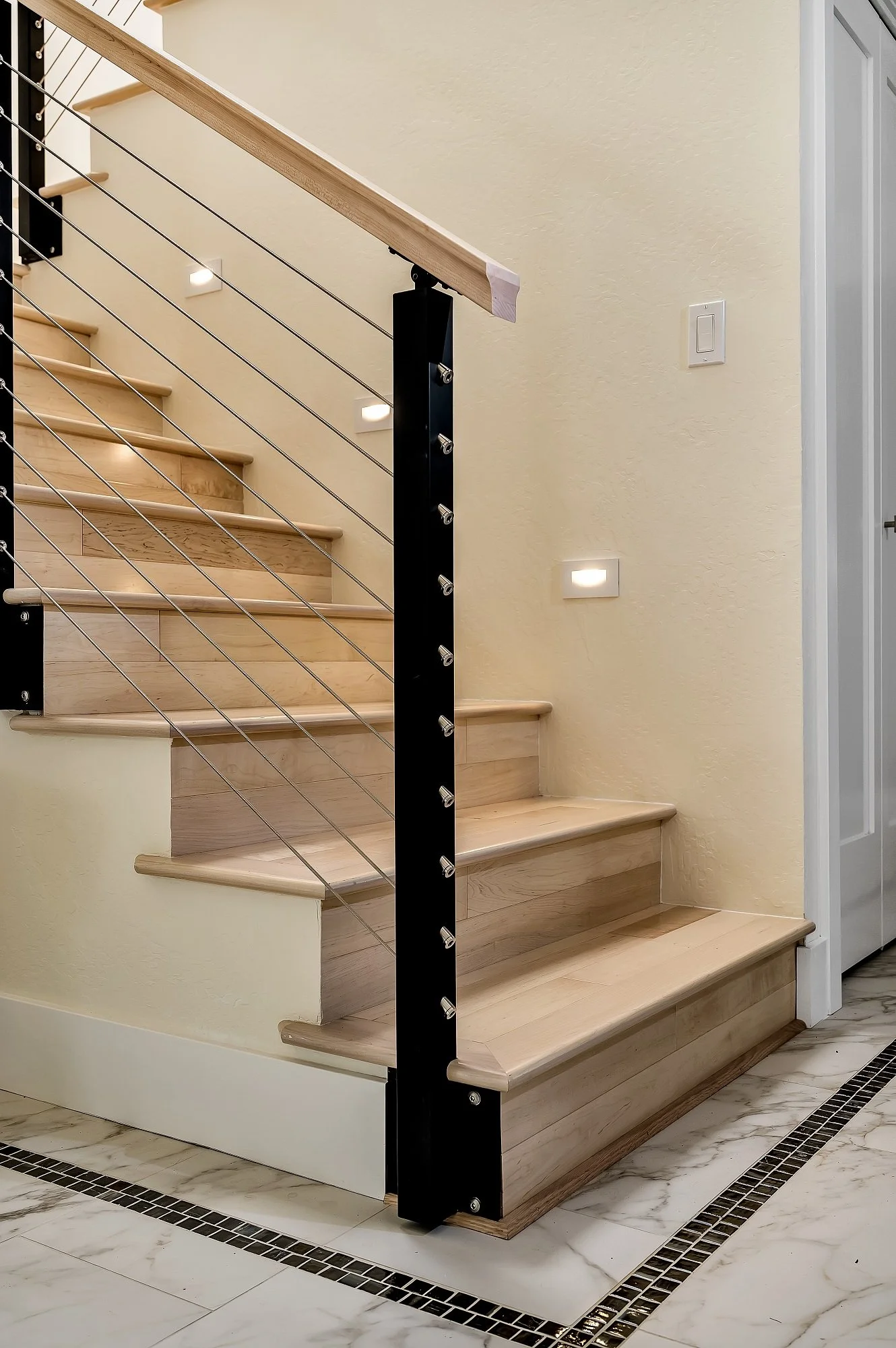 Custom stairway remodel in a Santa Cruz condo with wood treads, cable railing, and subtle integrated lighting.