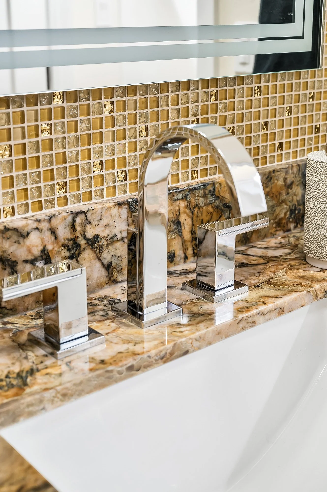 Modern bathroom faucet detail from a Santa Cruz condo remodel with mosaic tile backsplash and stone surfaces.